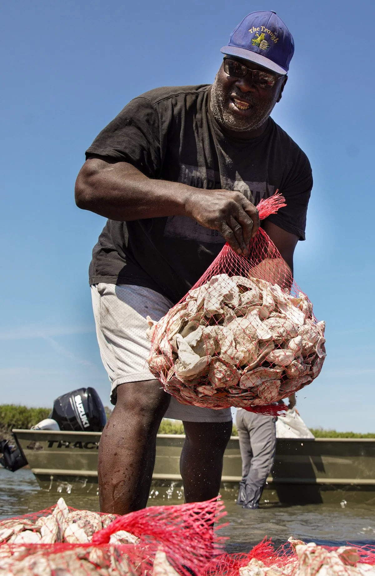 Maurice Bailey placing bags of oystershell into the marsh on Sapelo Island, GA