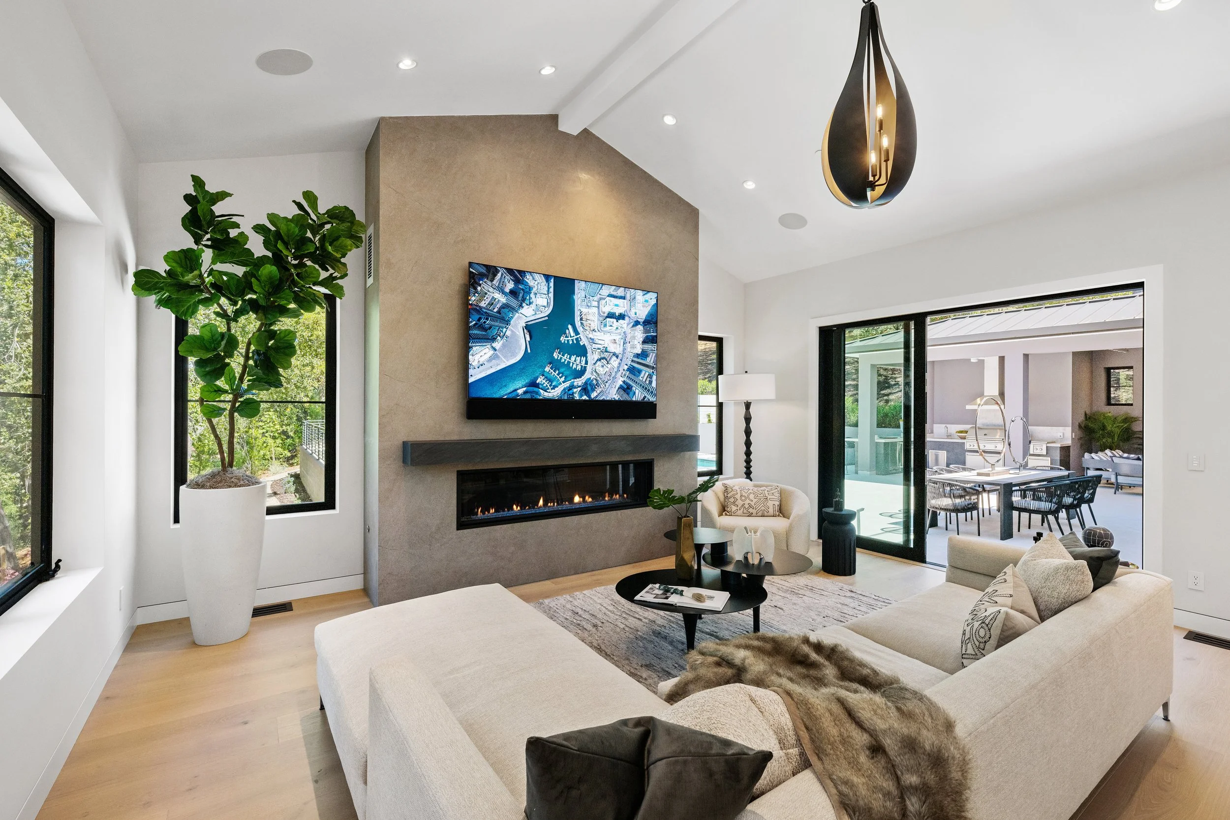 Modern living room with vaulted ceiling, fireplace and extra wide sliding glass doors, open to the patio. Designed by Young and Borlik Architects.