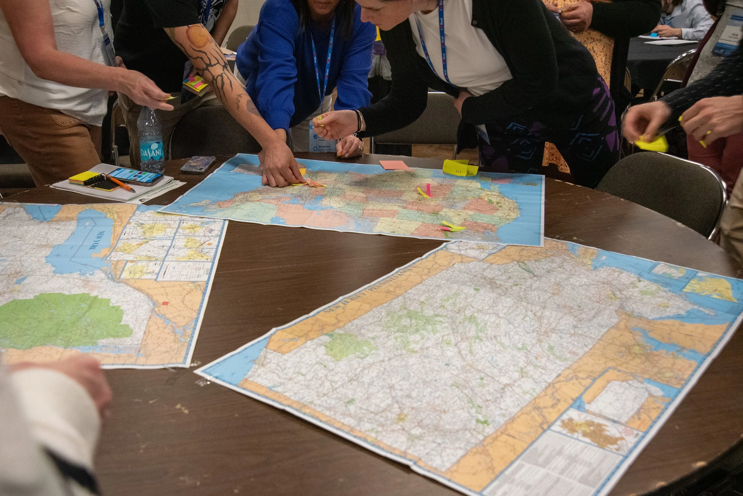 Dreama team members collaborating around a table with maps and planning materials, participating in a strategic discussion and brainstorming session.