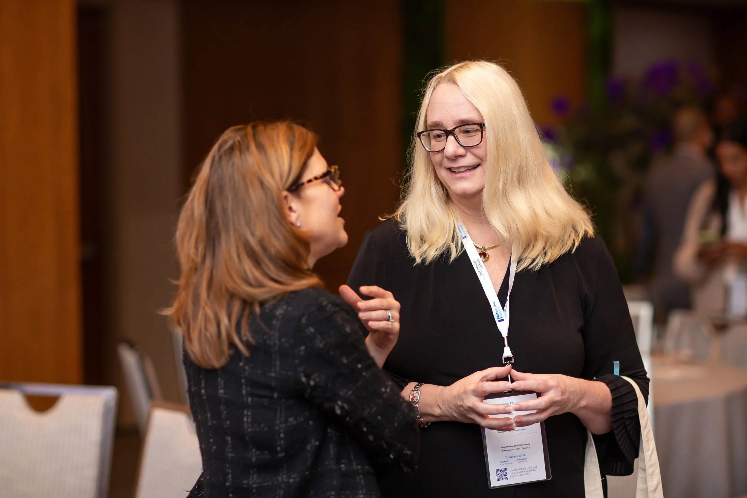 Dreama networking with an attendee at a professional conference, engaging in conversation and building meaningful connections.