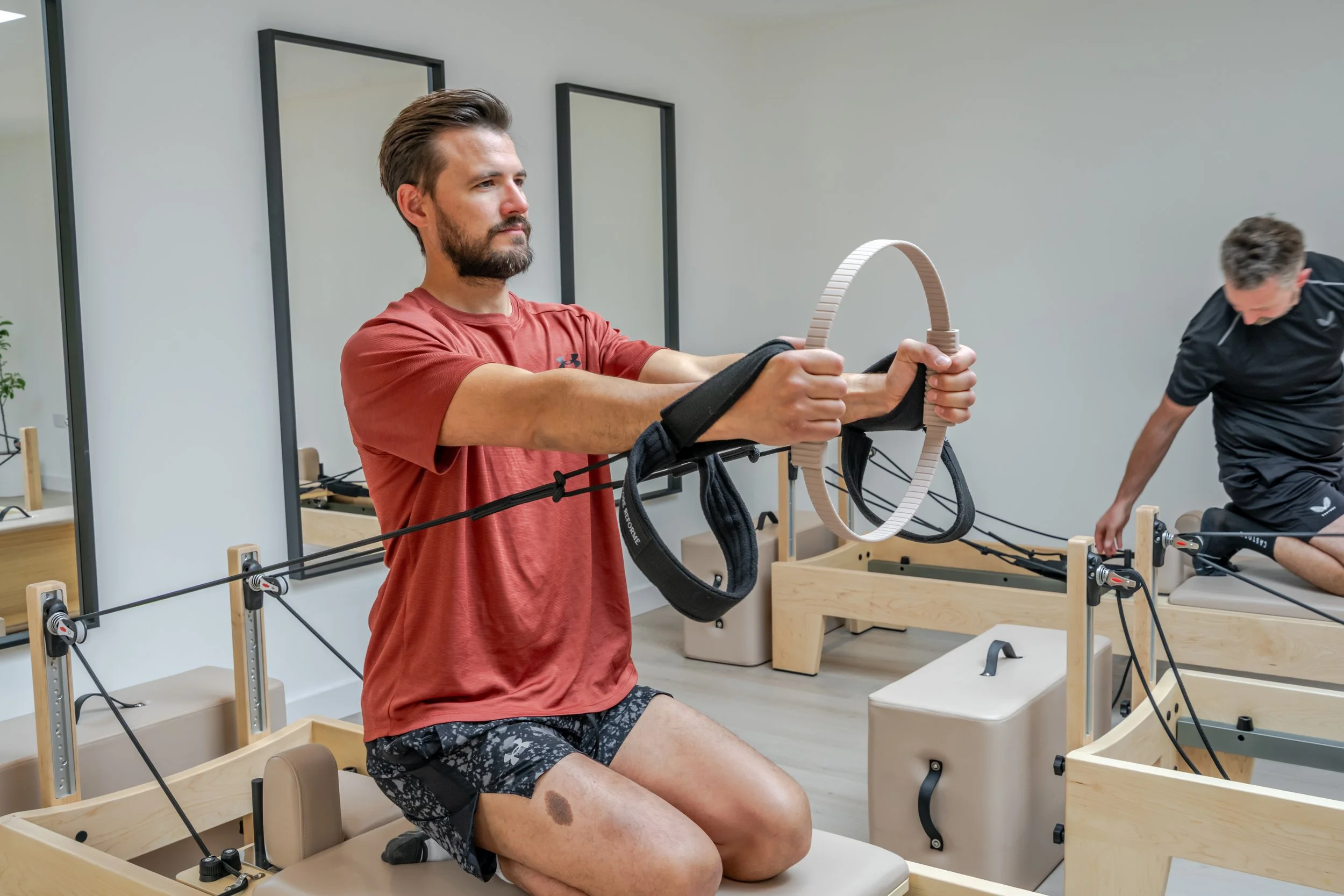 Man using a Pilates reformer machine during a strength-focused reformer Pilates session.