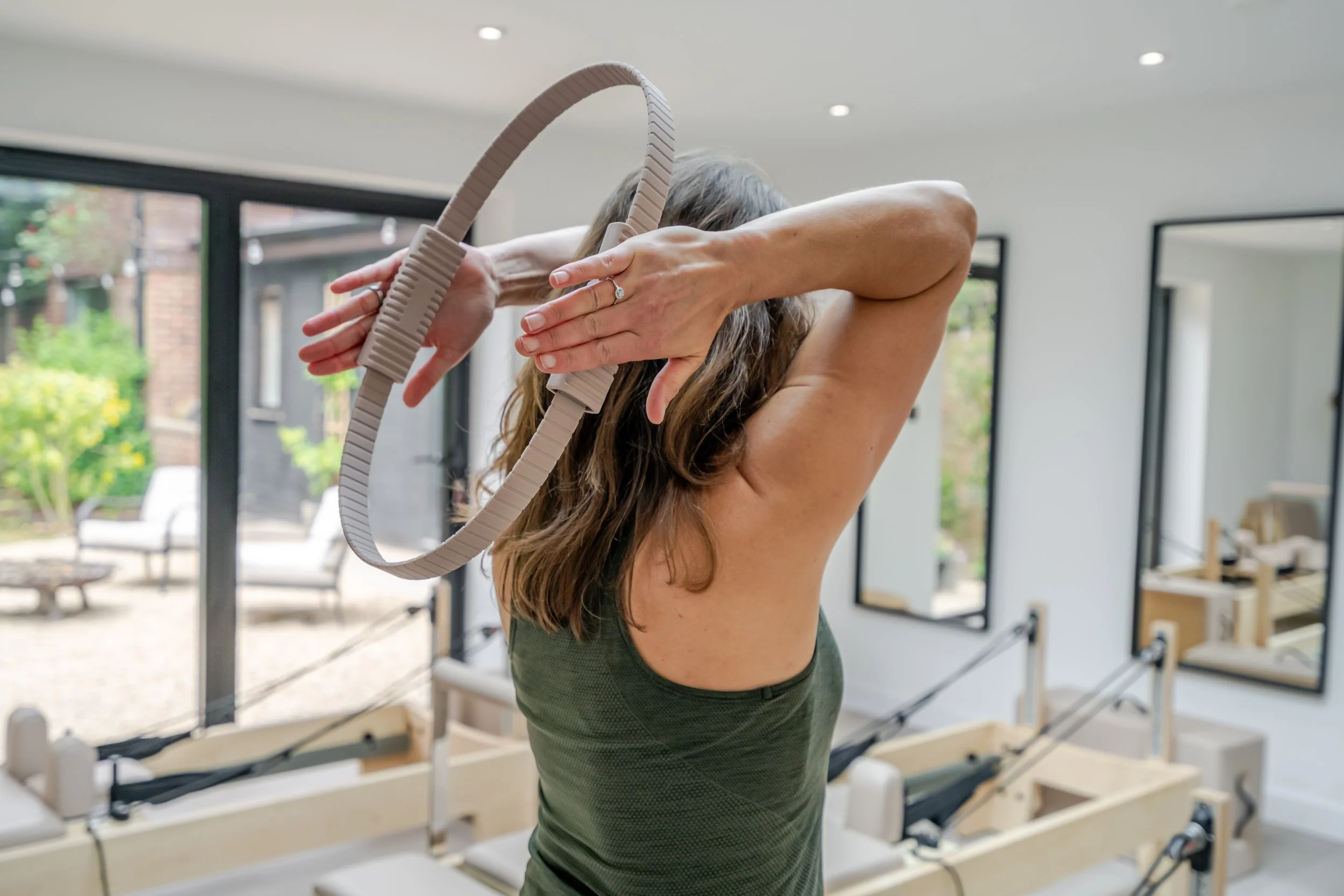 Client stretching during a reformer Pilates session in a bright boutique Pilates studio.