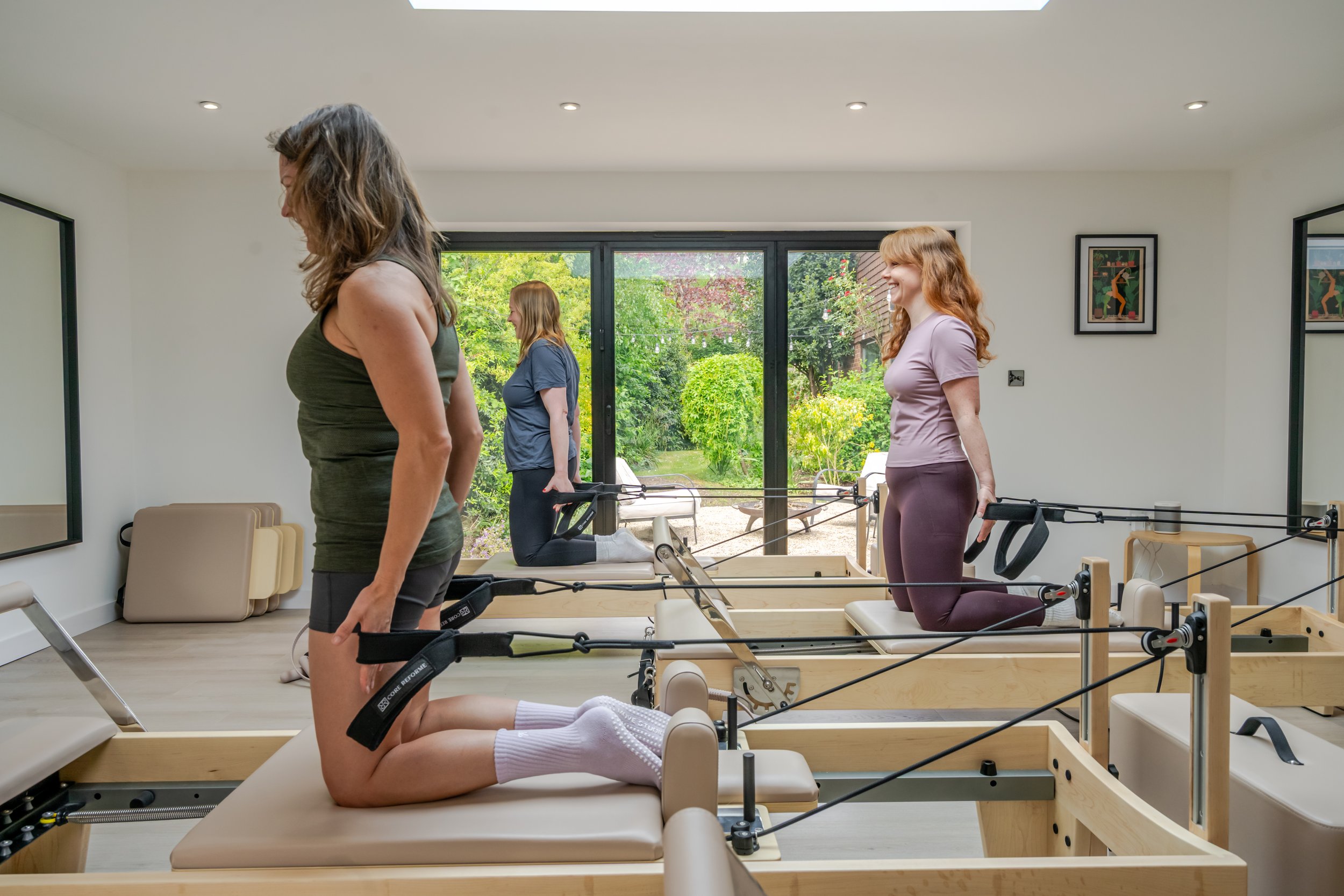 Small group reformer Pilates class in a bright and welcoming studio environment.