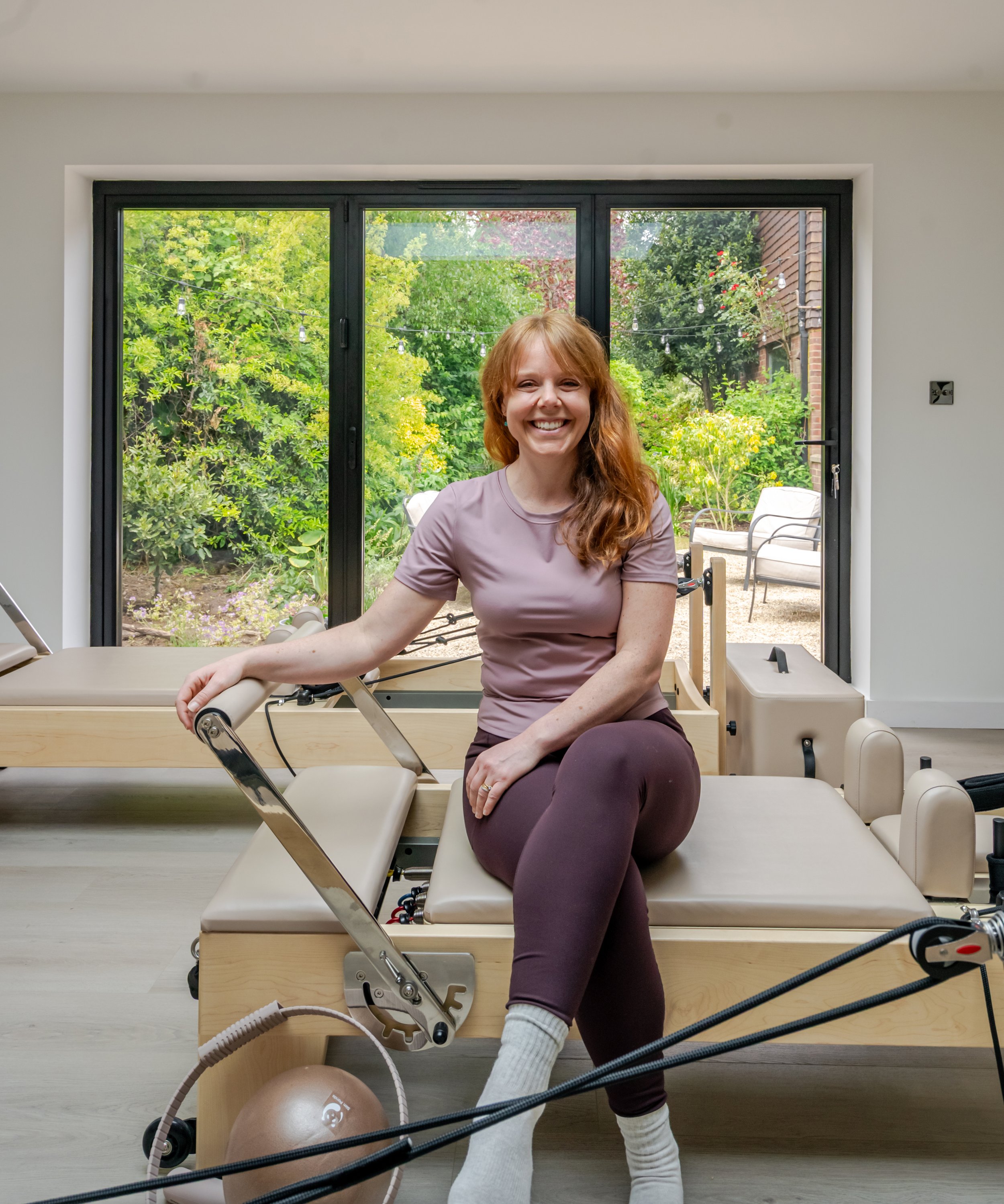 Woman sitting on a reformer Pilates machine at Reform With Marina studio in Whitchurch.