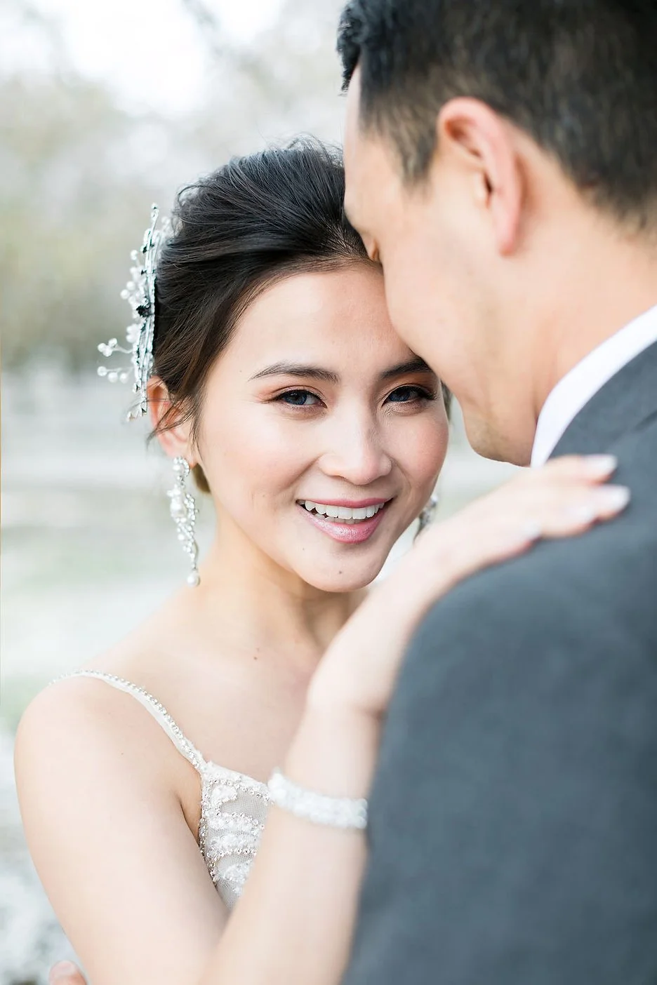 A bride and groom share an intimate moment outdoors, with the bride smiling and the groom leaning in close.