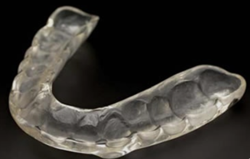 A transparent mouthguard with teeth impressions on a black background.