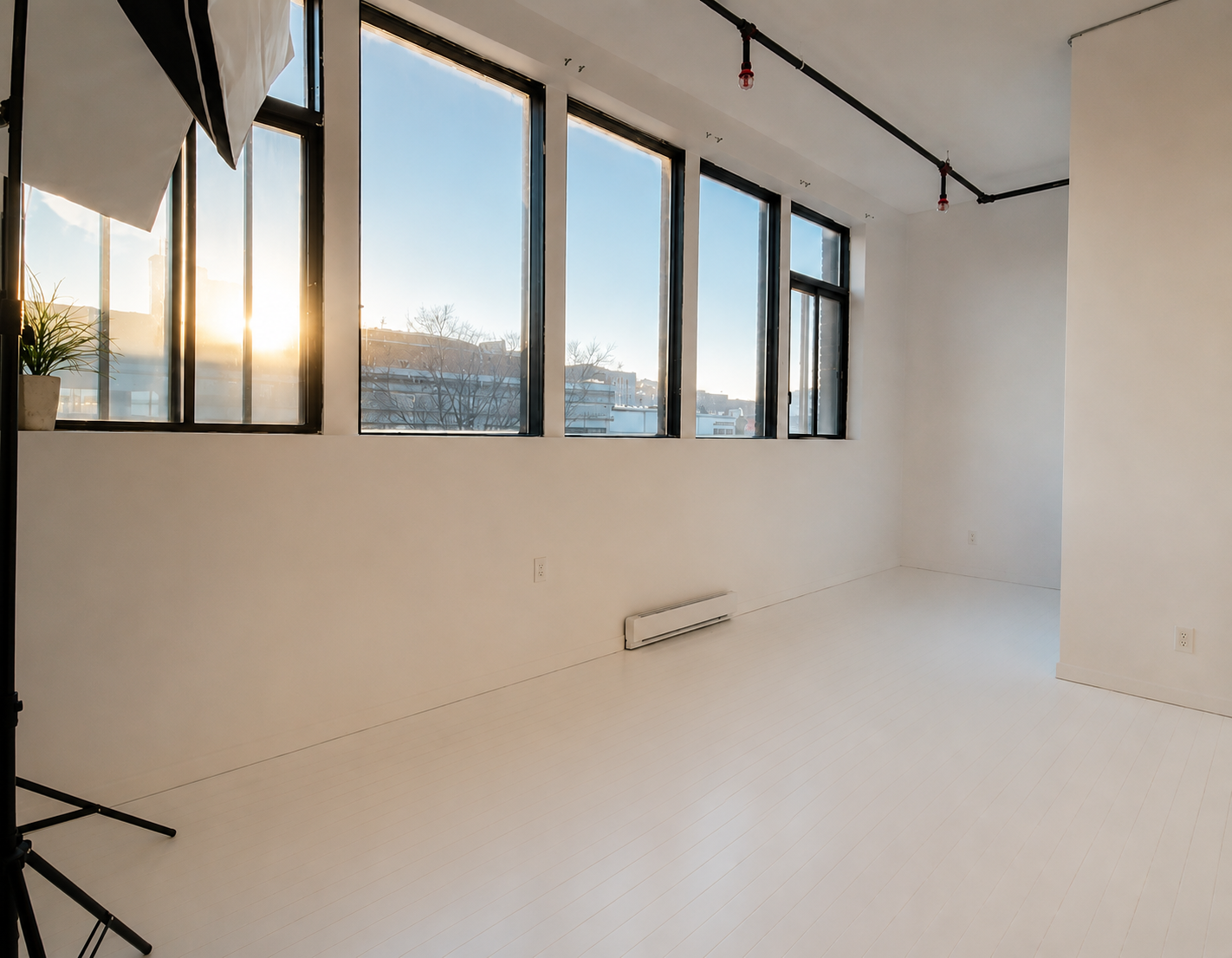 Space with large windows allowing sunlight and white walls. Minimalist style for photoshoots and videoshoots.