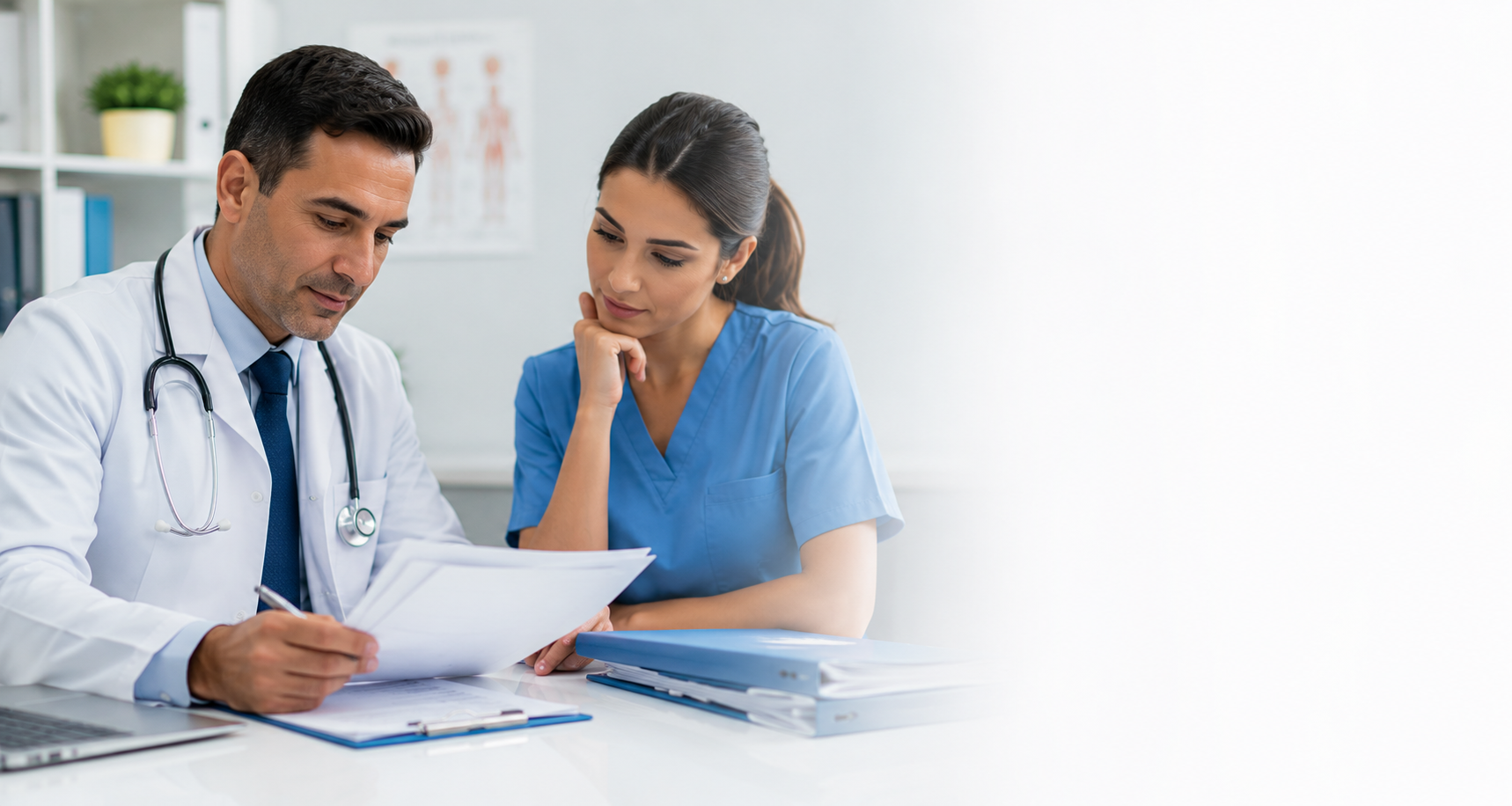 A male doctor and a female nurse reviewing medical documents together in a hospital or clinic setting.