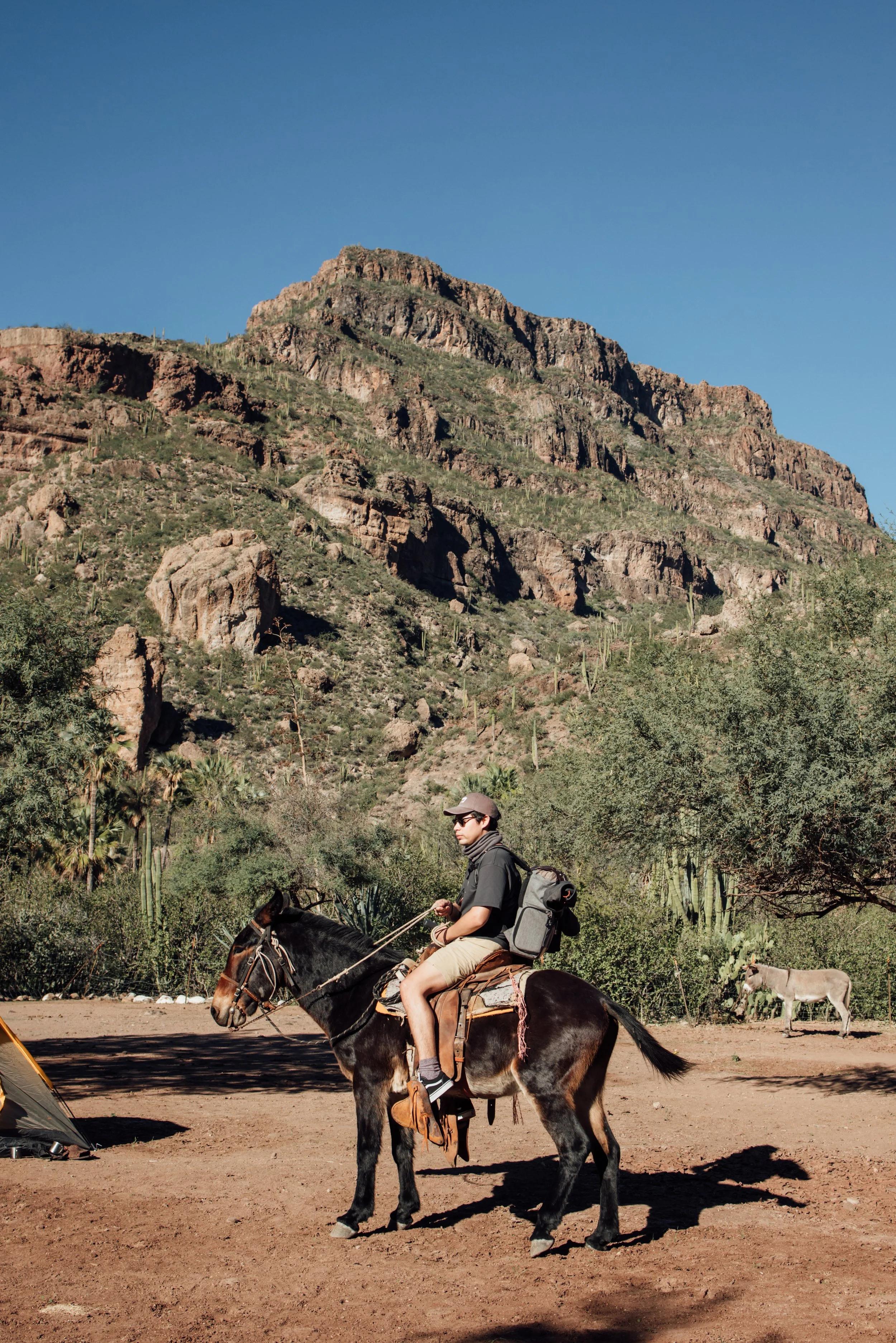 Visitante montando a caballo frente a las montañas de San Francisco de la Sierra, Baja California Sur.