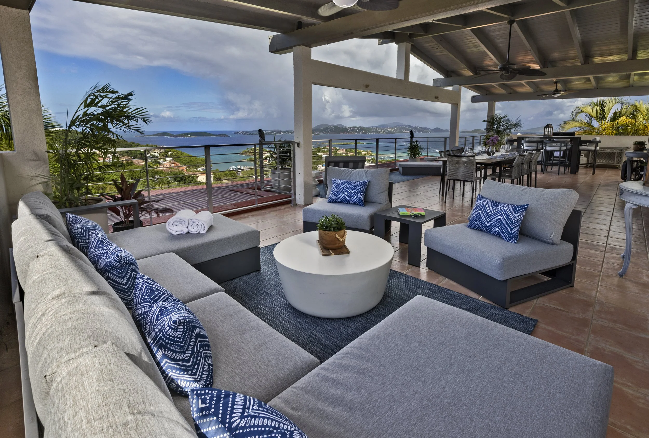 Mandavilla St. John USVI vacation rental A spacious outdoor balcony with modern furniture. The balcony has a view of the ocean with water, islands, and hills in the distance. Providing a relaxing setting with scenic ocean views.