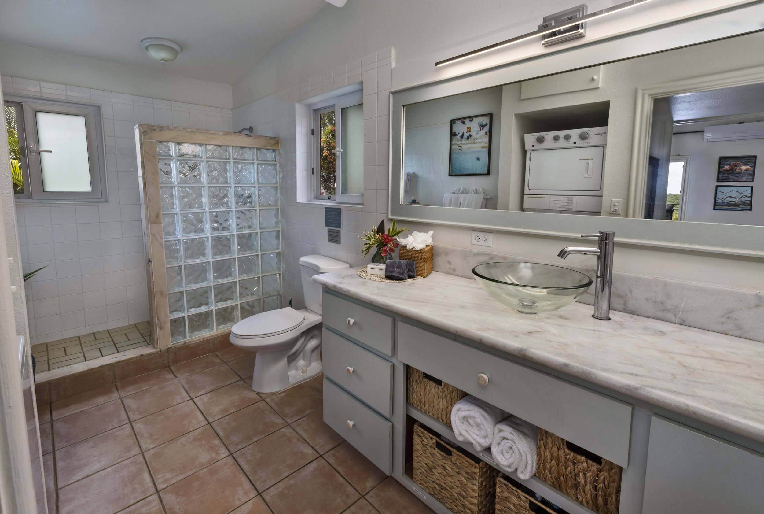 Mandavilla St. John USVI vacation rental Bathroom with a glass sink, mirror, washing machine, and shower area.