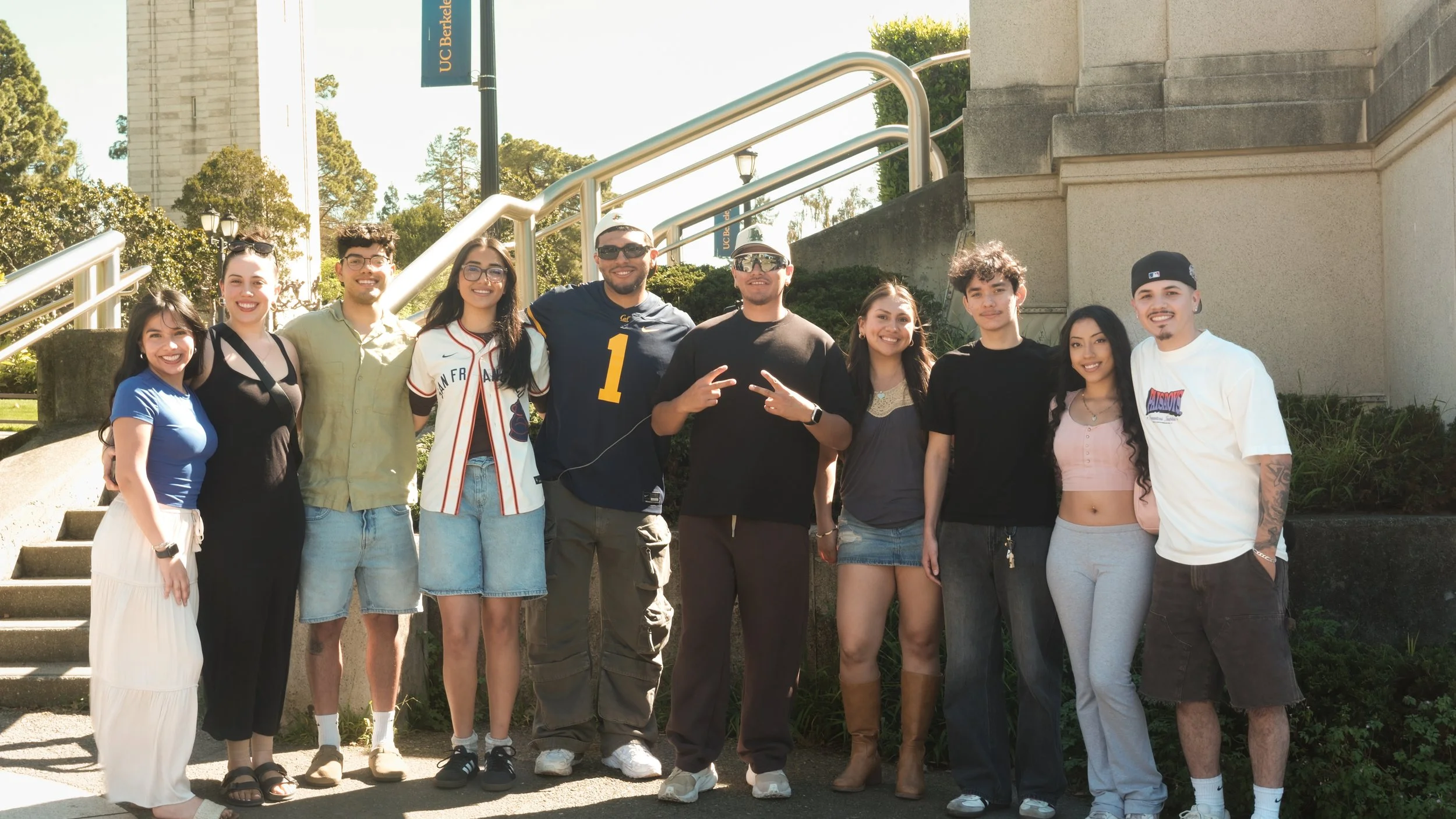 A diverse group of eleven young adults standing outdoors on steps, smiling for a photo.