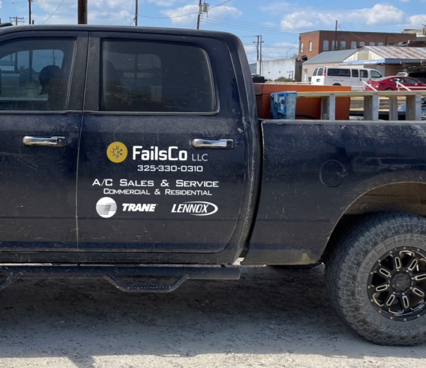 A black pickup truck parked outdoors with dirt on its body, featuring company branding on the door for FailsCo LLC, an HVAC sales and service business. The truck bed holds various tools and equipment. In the background, there are buildings, vehicles, and a partly cloudy sky.