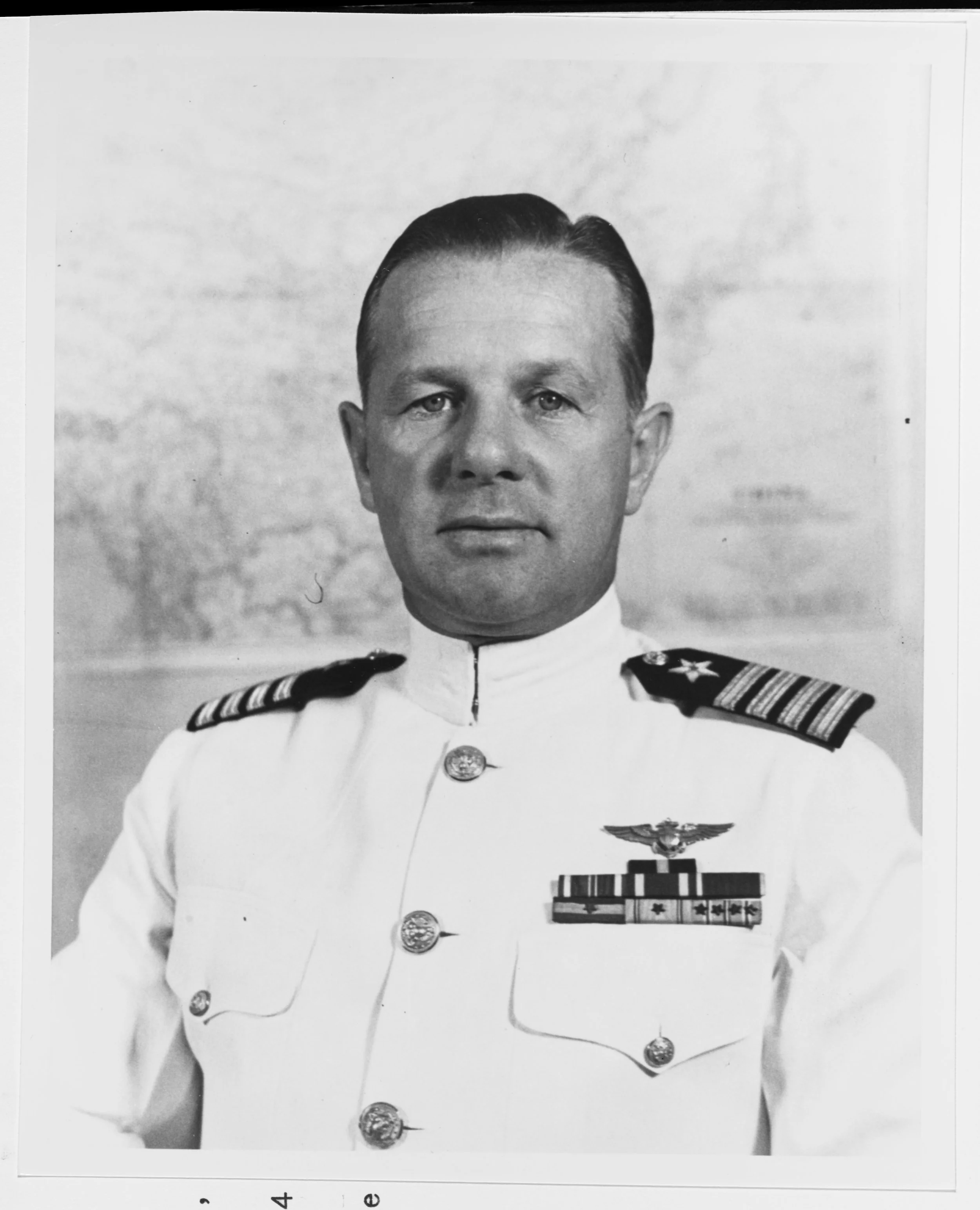Black and white photo of two men in military uniforms and hats talking on a boat. Several other men are in the background.