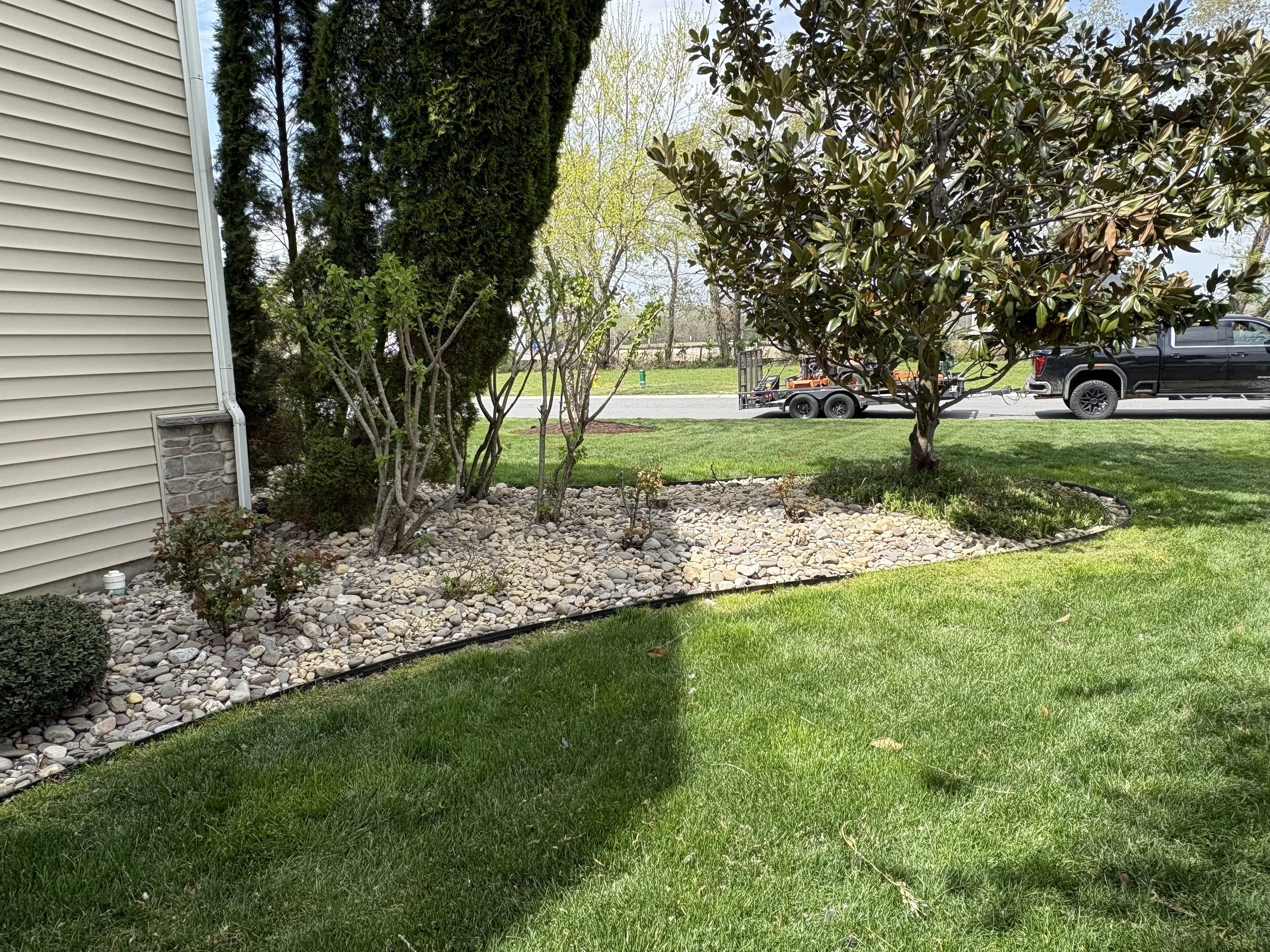 Front entry landscaping bed with fresh mulch and trimmed shrubs after service in Delaware