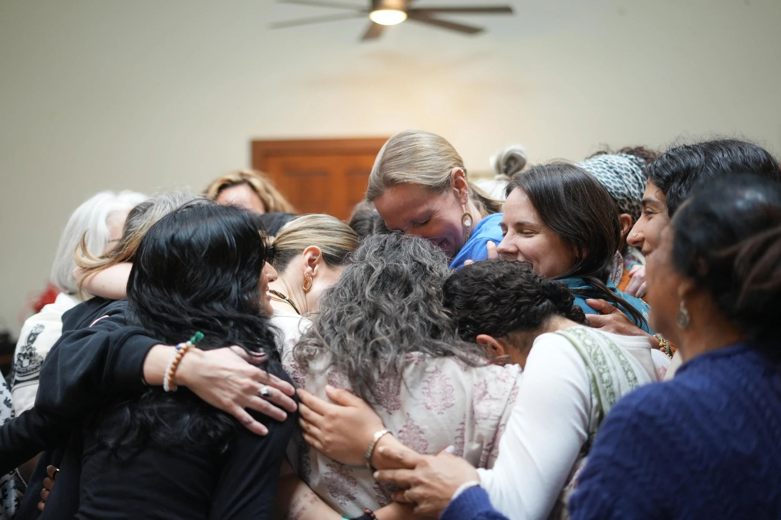 A diverse group of people embracing in a tight hug, expressing support and compassion.