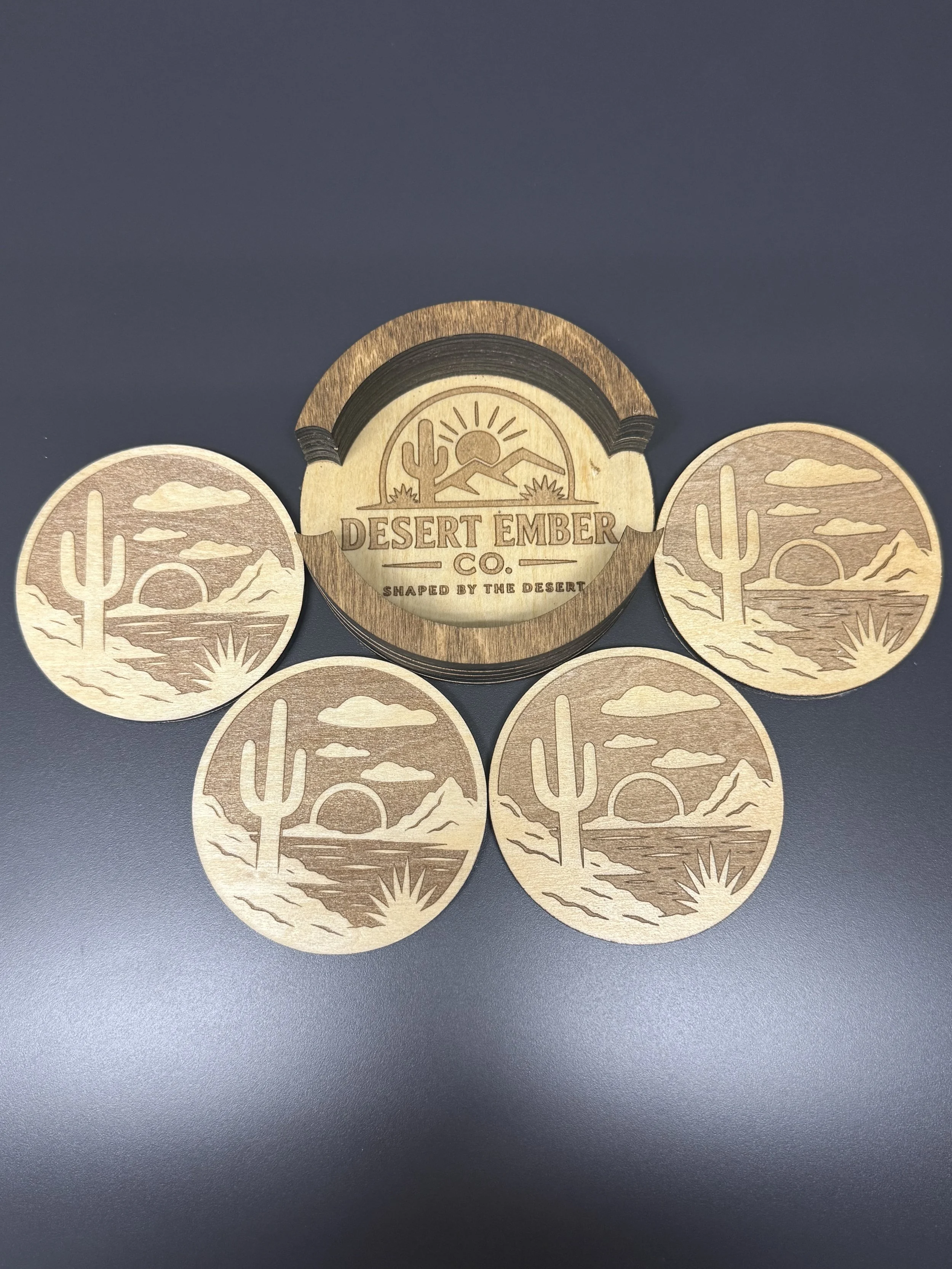 Wooden coasters with desert landscape design including a cactus, mountains, and sun.