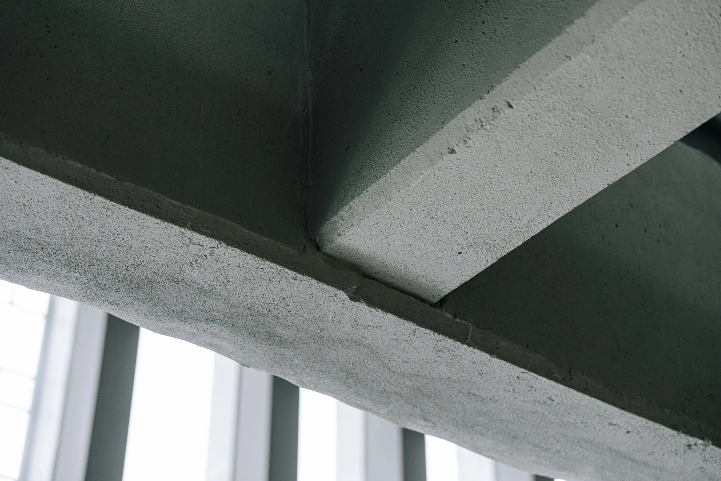 Close-up view of the corner where a concrete wall meets a concrete ceiling, showing textured surfaces and sharp angles.