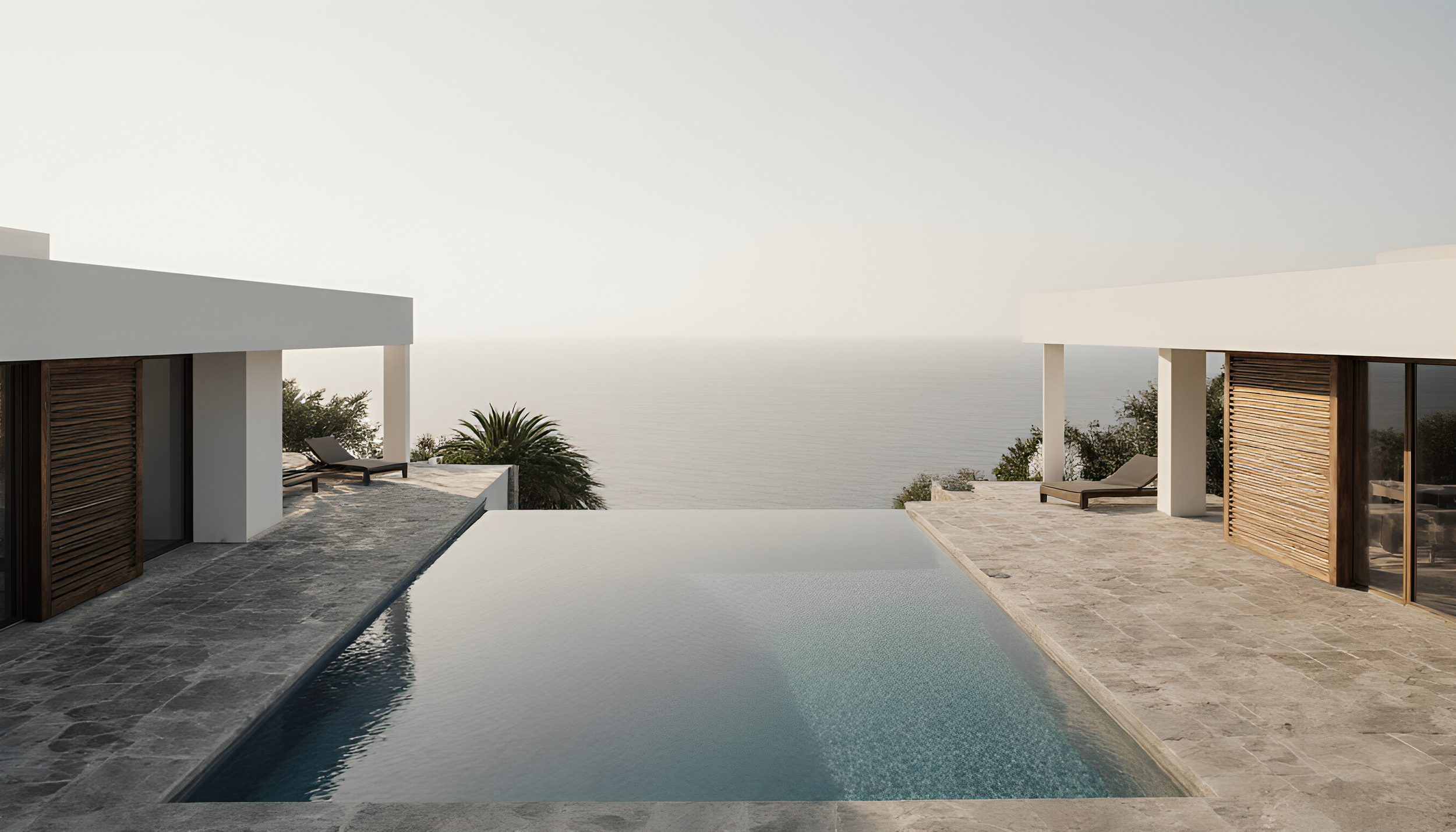 Modern poolside area with chairs, overlooking the ocean and a cloudy sky.