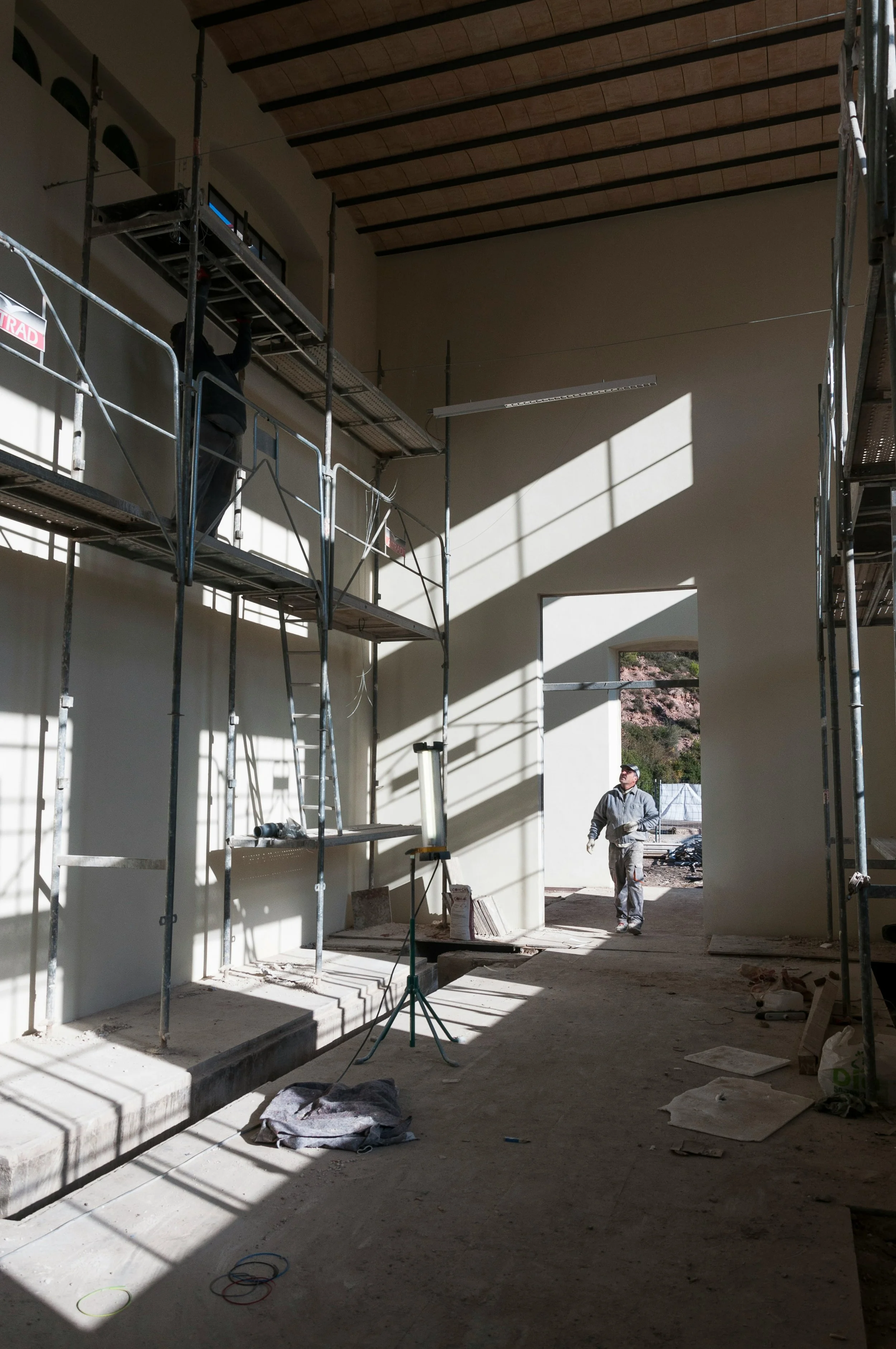 Construction workers building interior with scaffolding and sunlight streaming through windows
