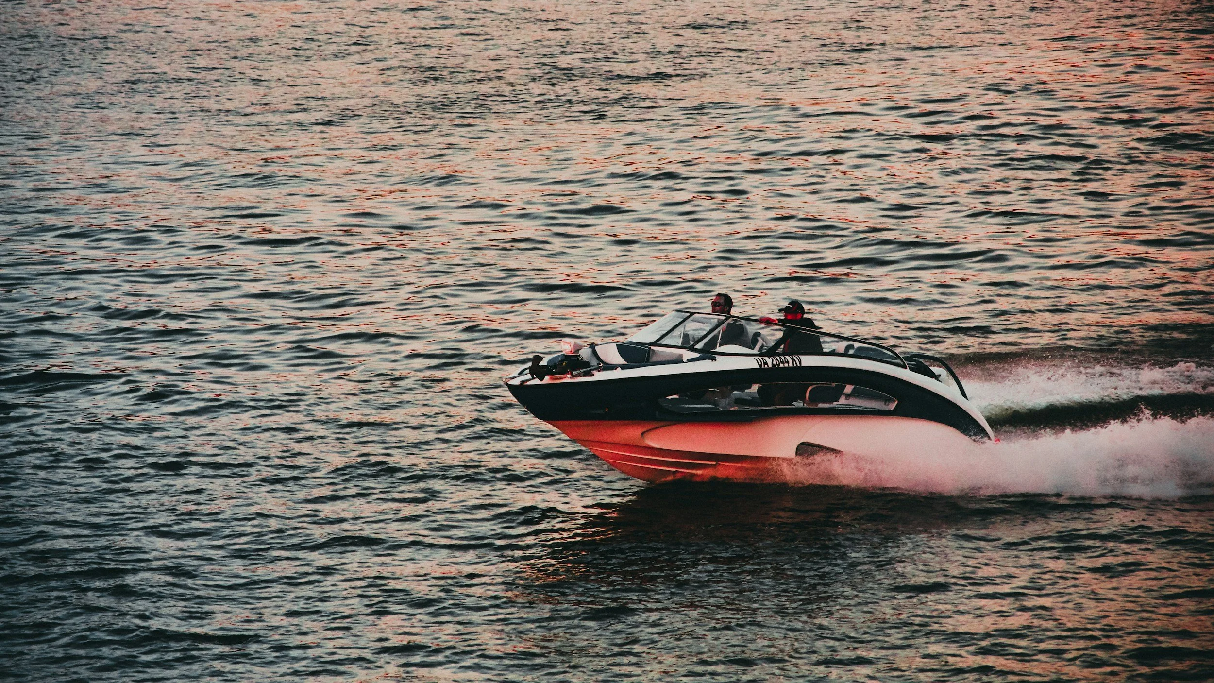 Modern performance boat cruising across Grand Lake water at sunset in Northeast Oklahoma.