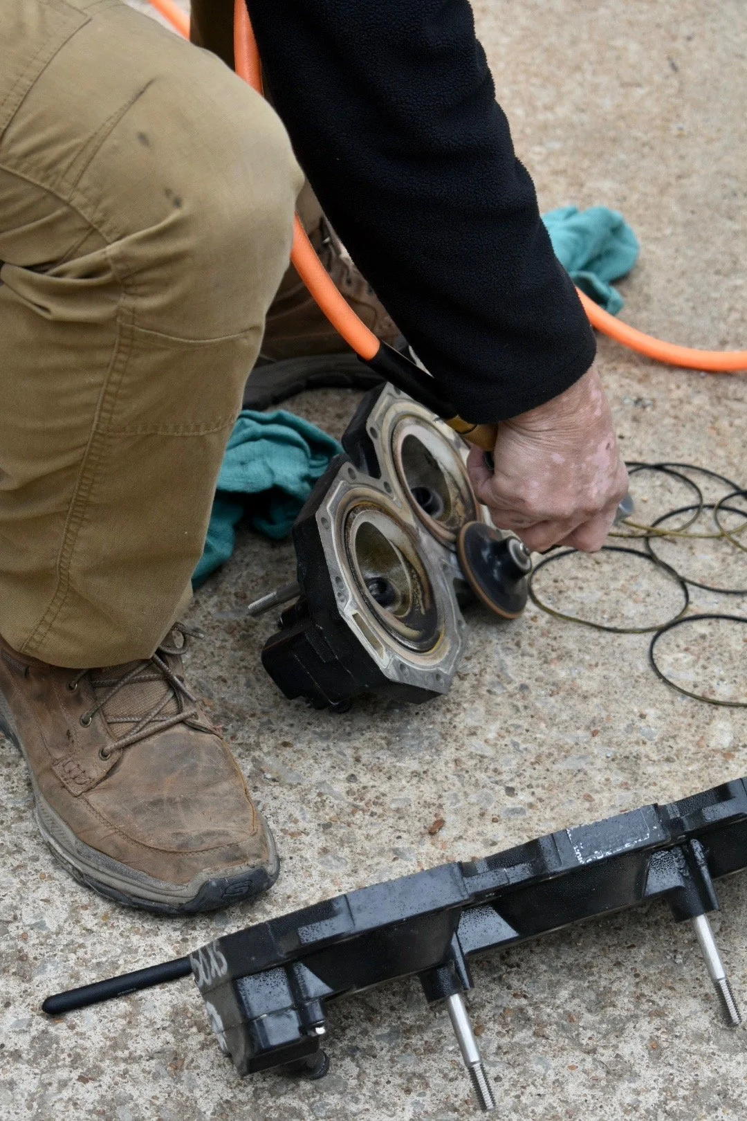 Marine technician cleaning and servicing outboard engine components during a boat motor repair in Grand Lake, Oklahoma.