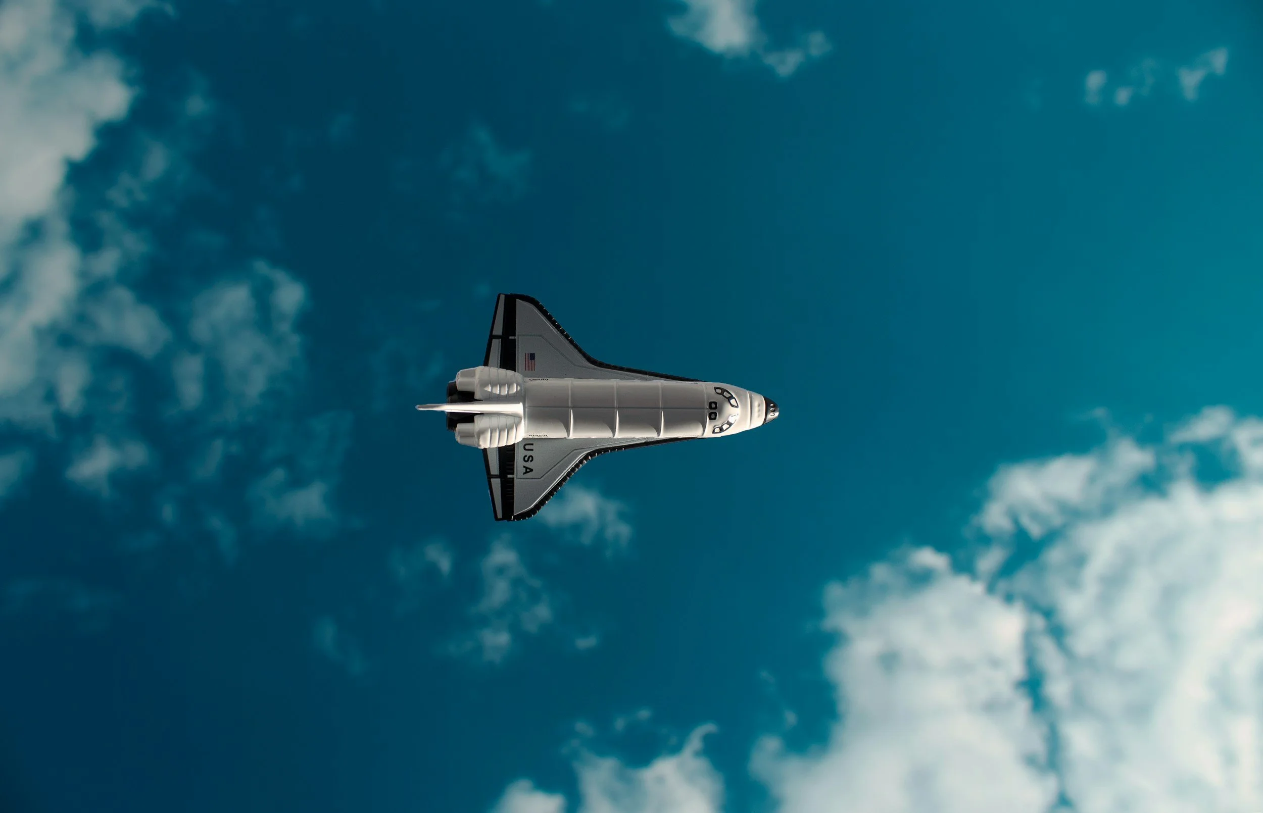 A space shuttle flying through a partly cloudy sky.