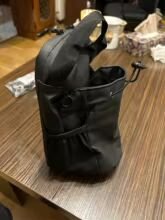 Black handbag on a table with a white object inside and some items in the background.