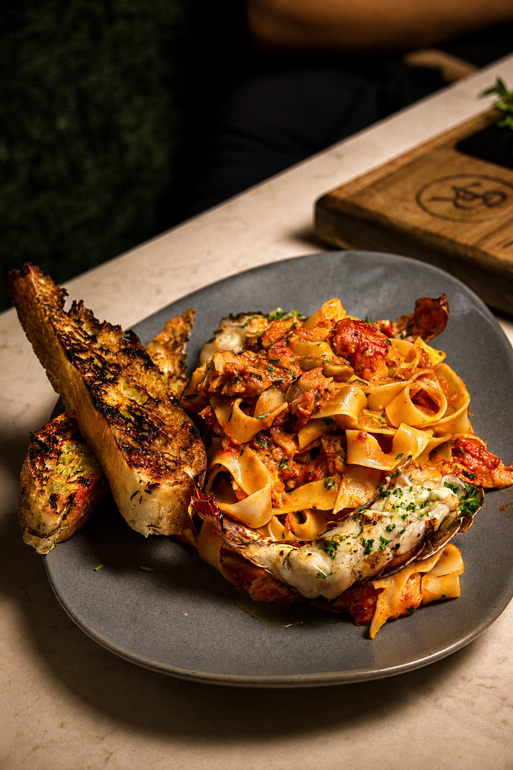 Plate of fettuccine pasta with shrimp, garnished with herbs, served with garlic bread on a dark plate.
