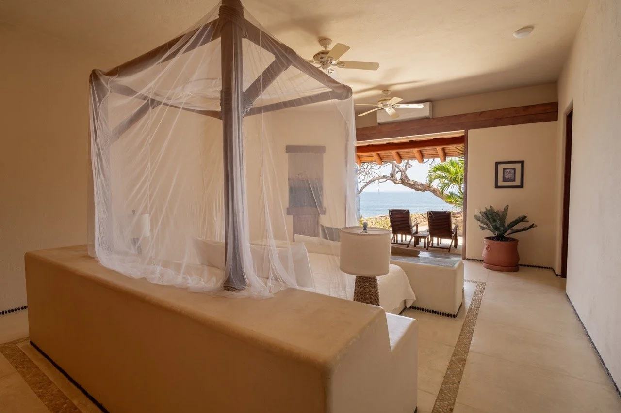 Habitación con vista al mar, sillones en la terraza, árbol y plantas decorativas.