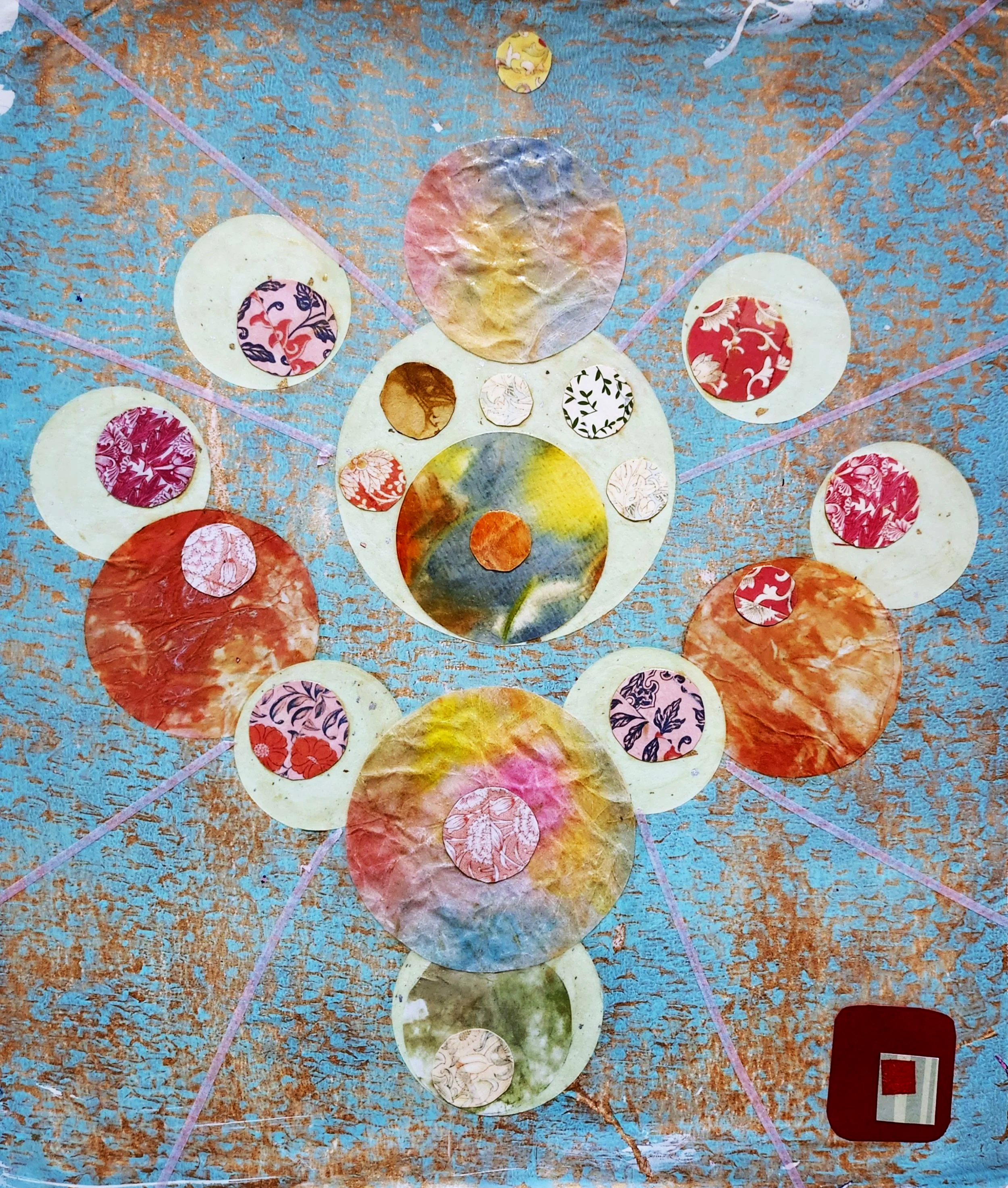 Une œuvre artistique abstraite composée de cercles colorés en papier déchiré, disposés en une formation en spirale ou en mandala sur un fond bleu avec des lignes roses.