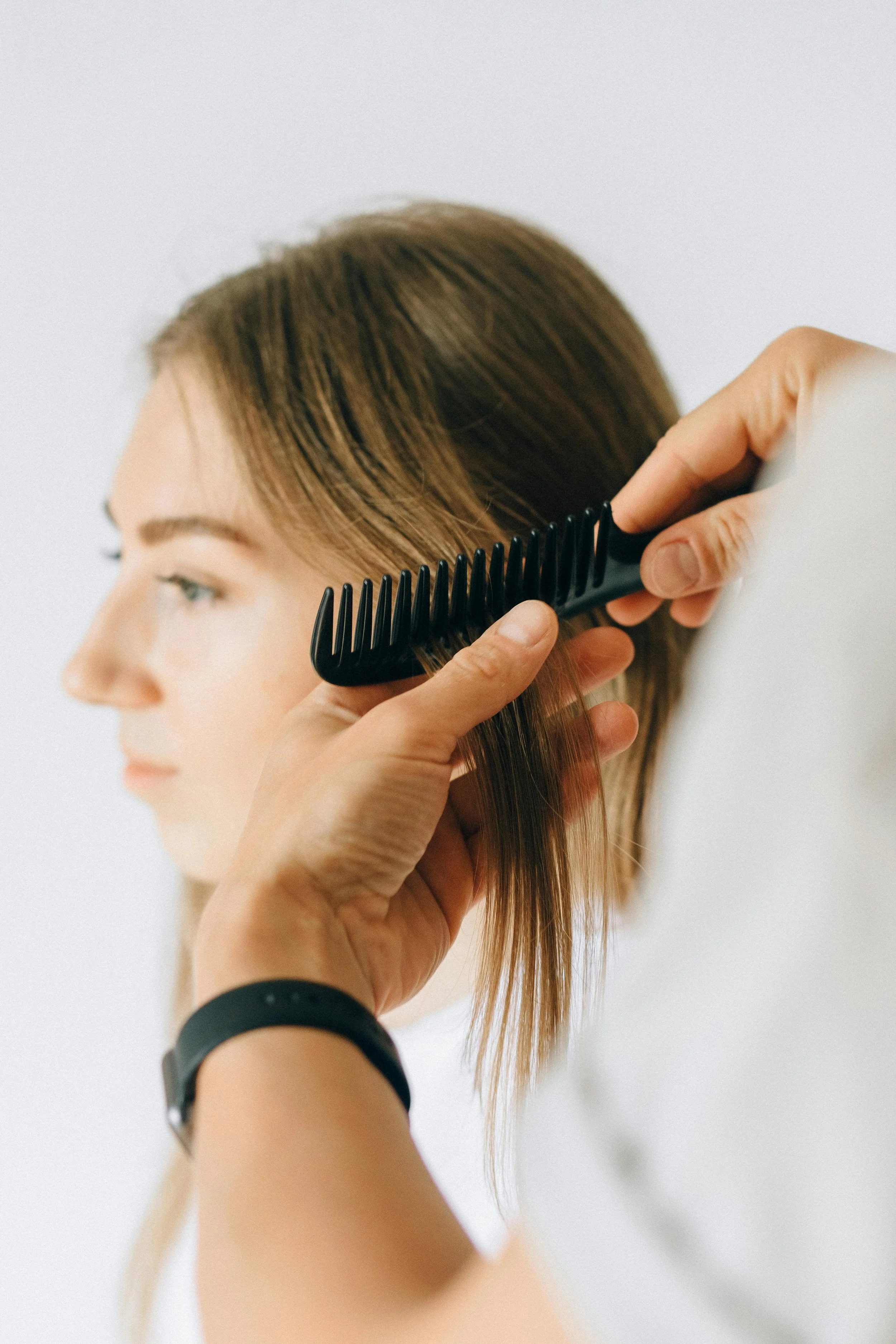 Close-up of a person receiving a haircut, with hair being combed and styled.