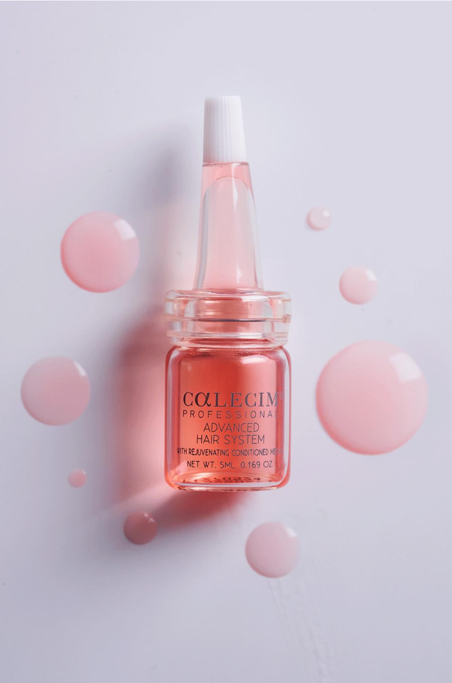 A small pink bottle of professional advanced hair serum labeled 'CALCIM' with a white cap, surrounded by pink spherical objects on a white background.