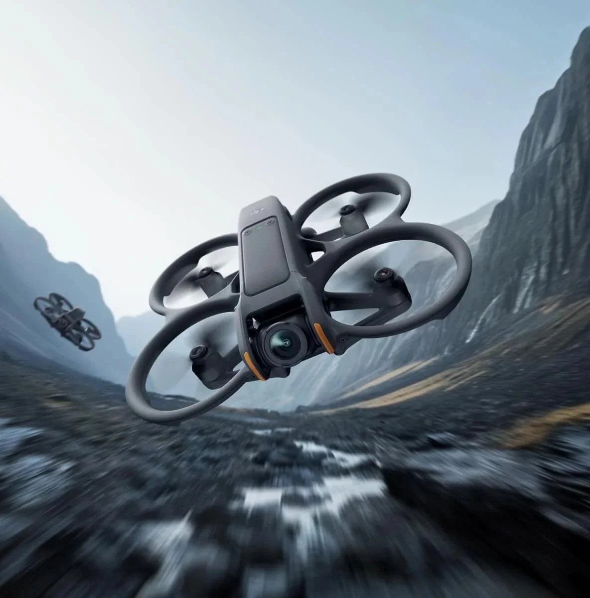 A drone flying over a rocky landscape with mountains in the background.