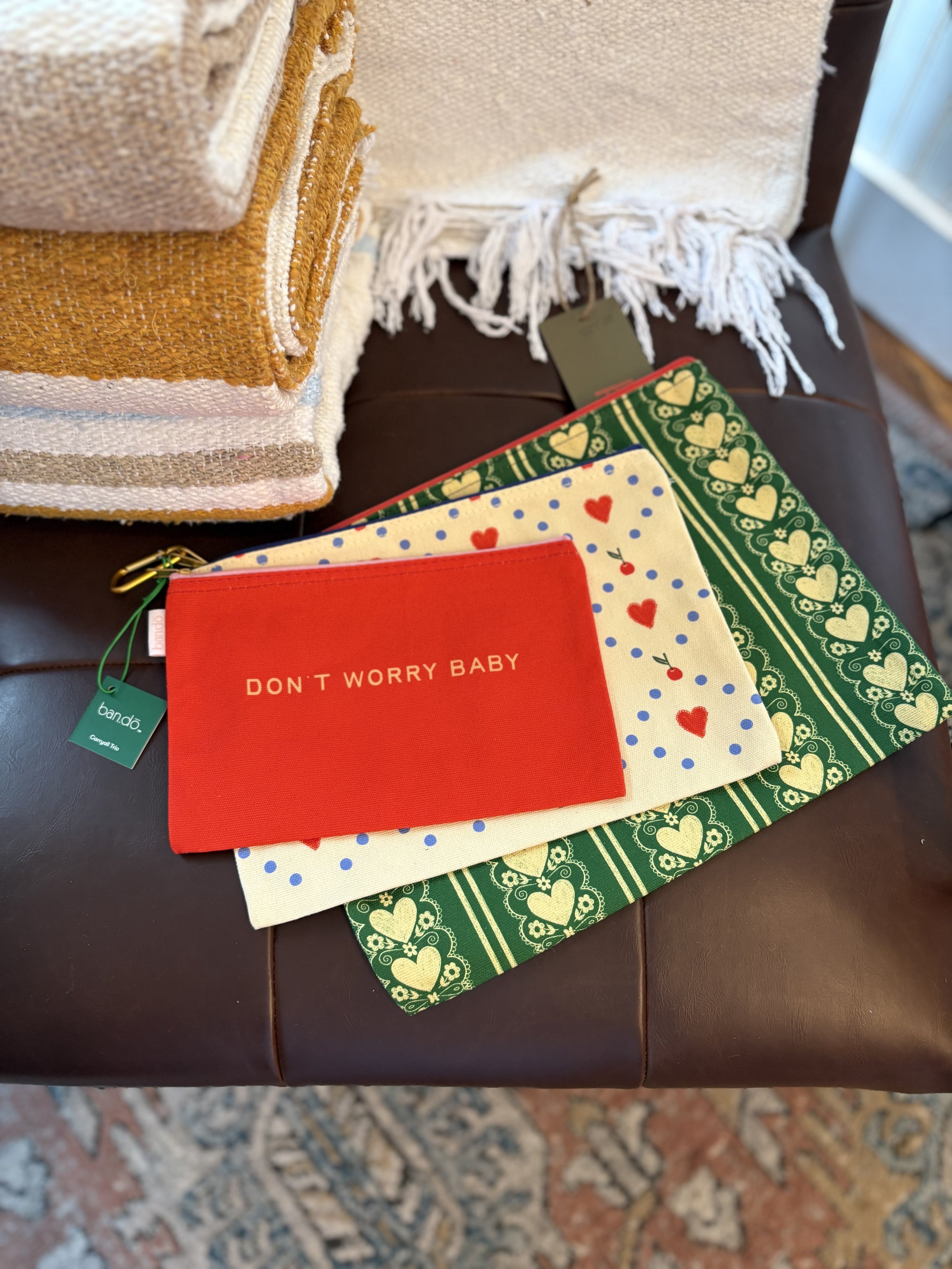 Stacked folded towels and colorful fabric napkins with holiday patterns on a dark leather surface.