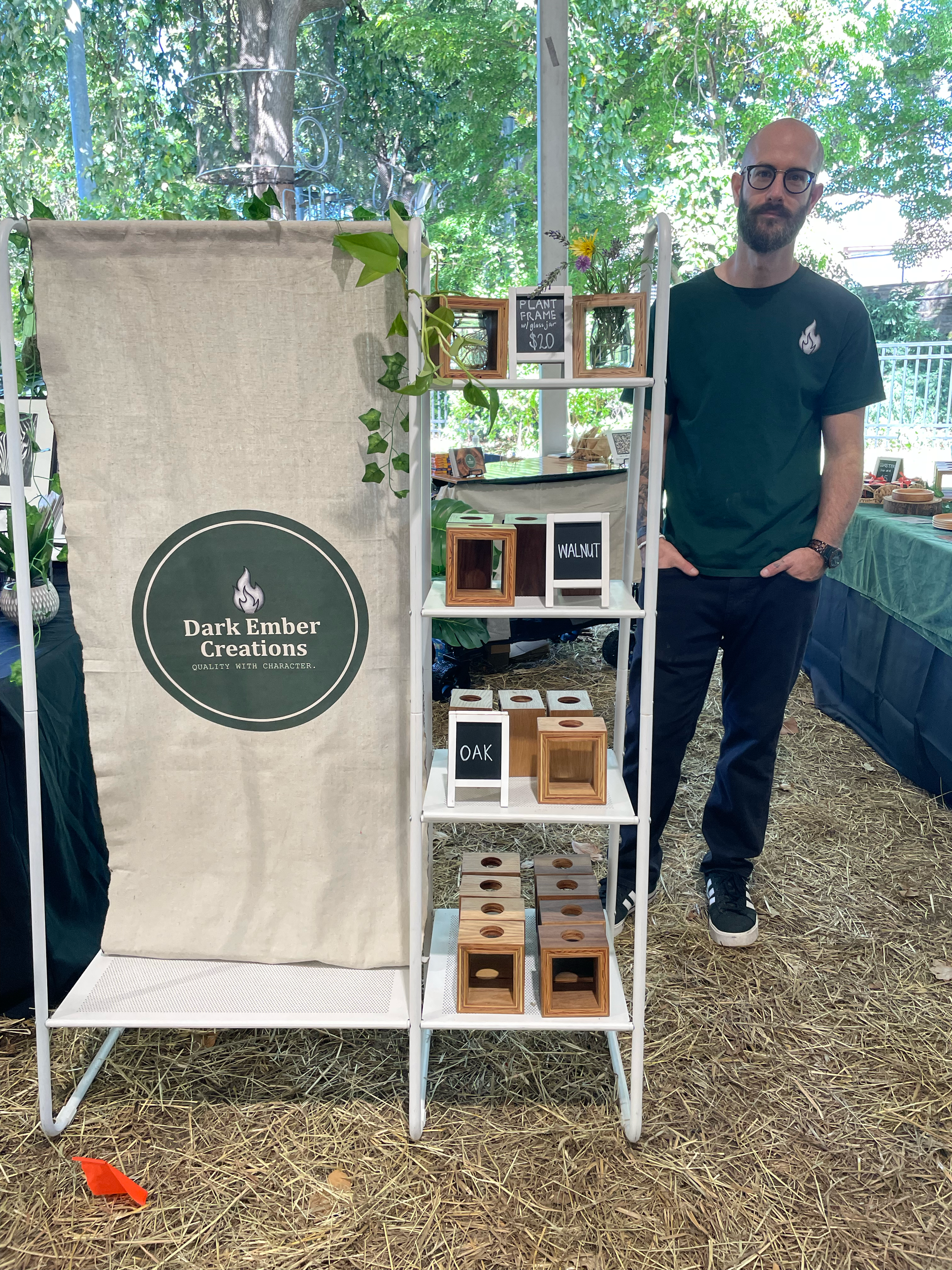 Daniel Cohen (DEC) at his market booth with his sign and plant frames