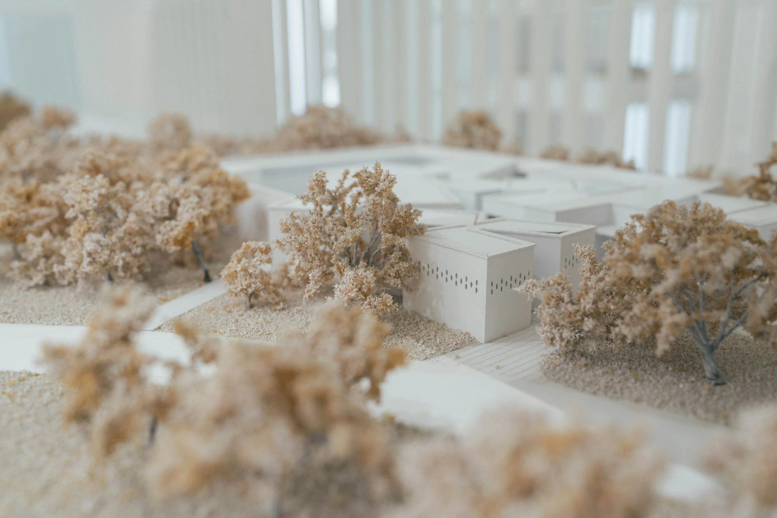 A detailed architectural model of a building surrounded by miniature trees.
