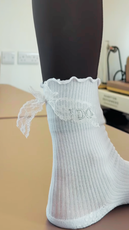 Close-up of a foot wearing 'I DO' pilates grip socks in a pilates studio setting.
