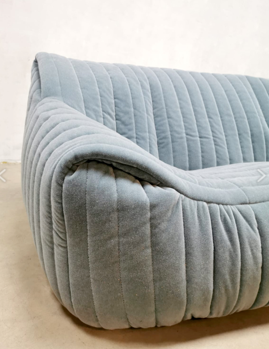 Close-up of a light gray, plush, quilted sofa with vertical stitching. The Annie Hieronimus Sandra sofa.