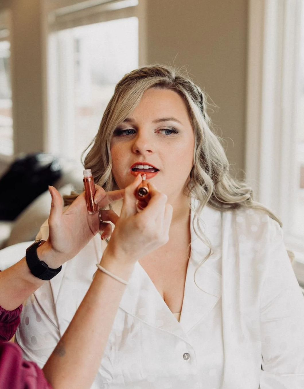 A Makeup artist is doing a brides makeup. It is neutral glam. with a makeup artist applying lipstick.