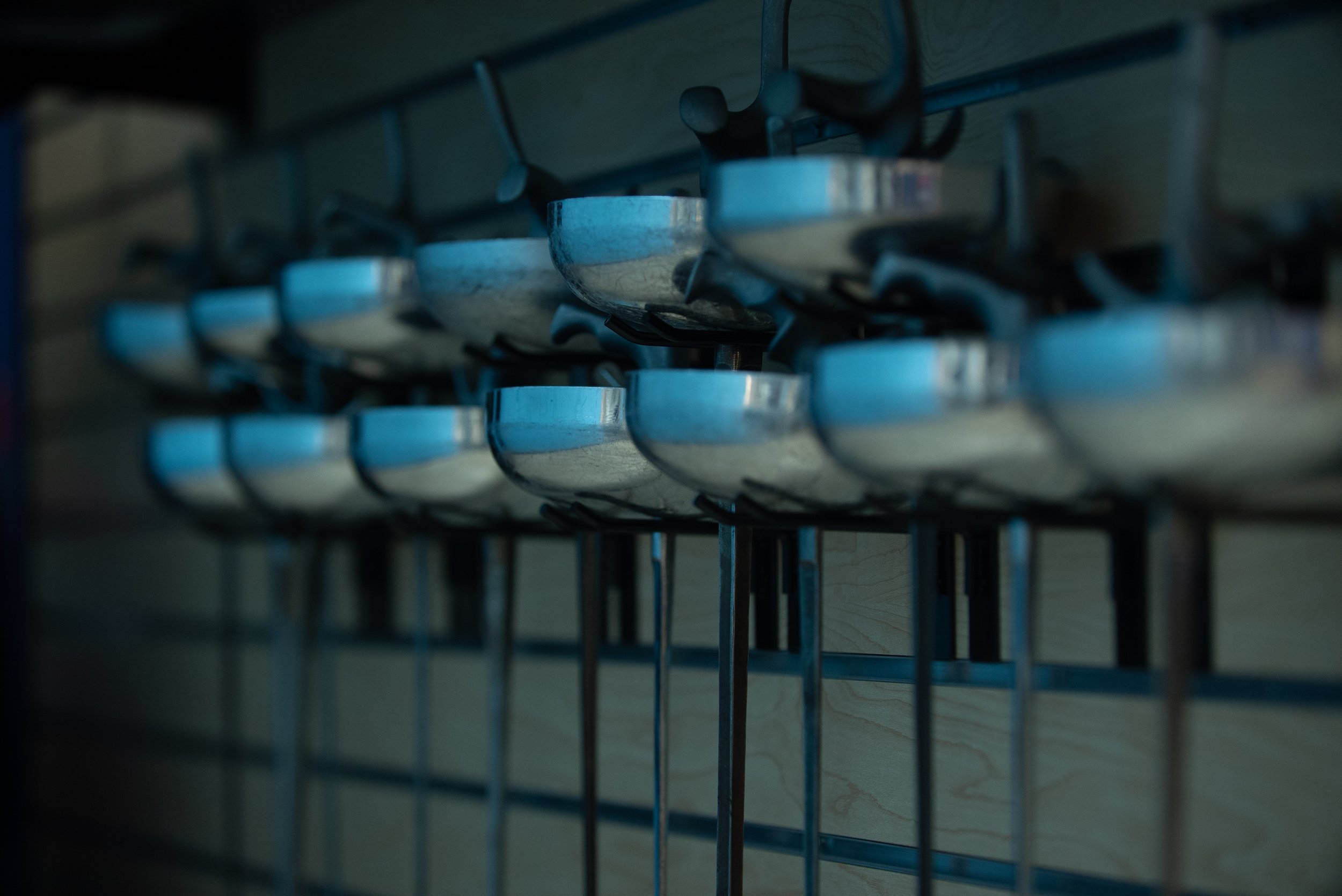 A close-up view of several epees on a storage rack.