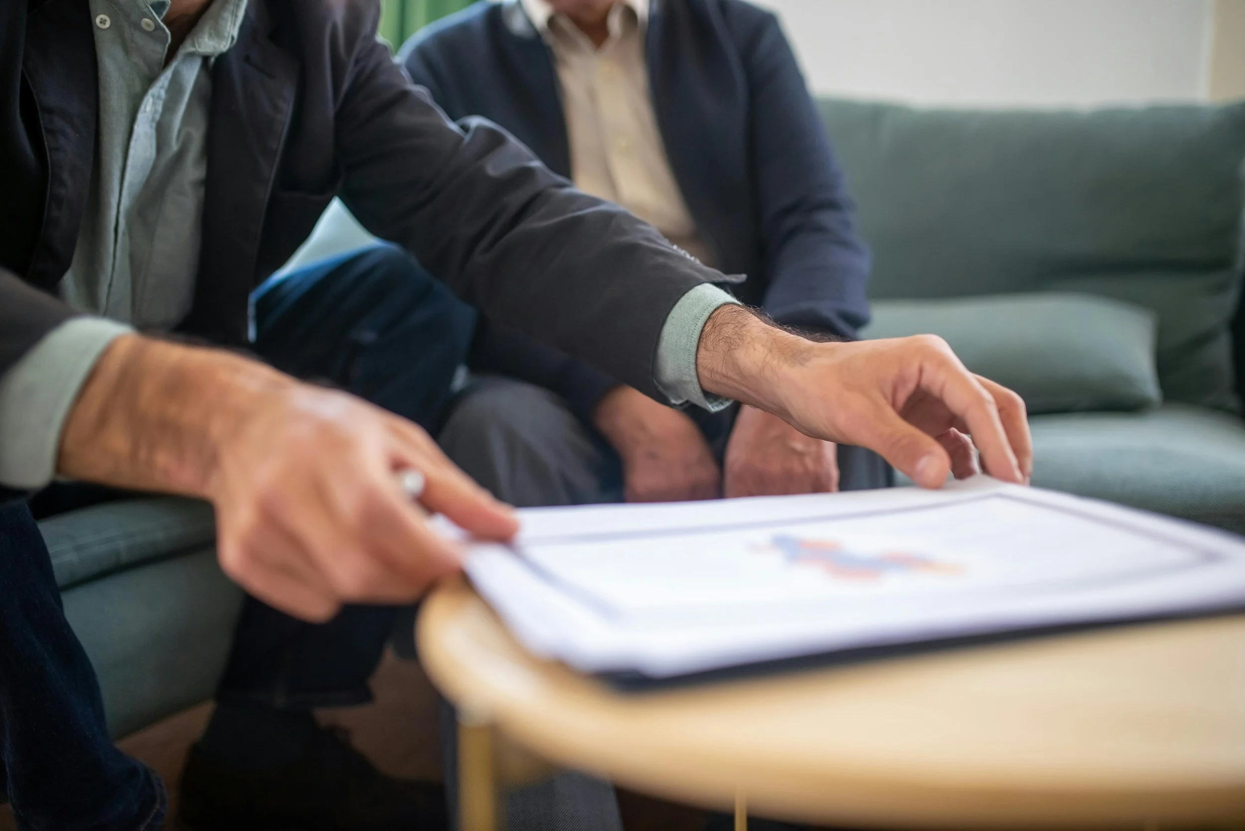 People sitting around a table, discussing or reviewing documents in an indoor setting.
