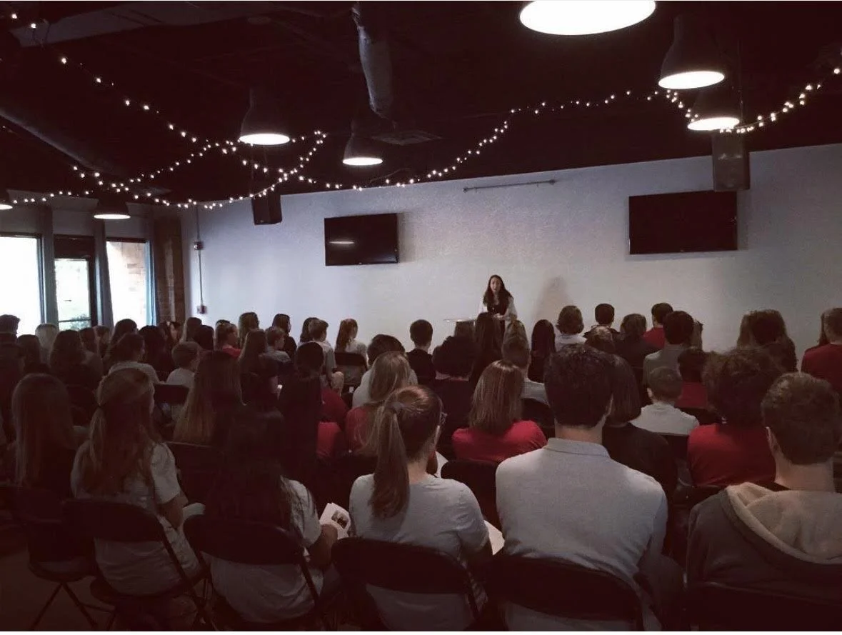 Woman speaking in front of a crowd during a workshop on community building