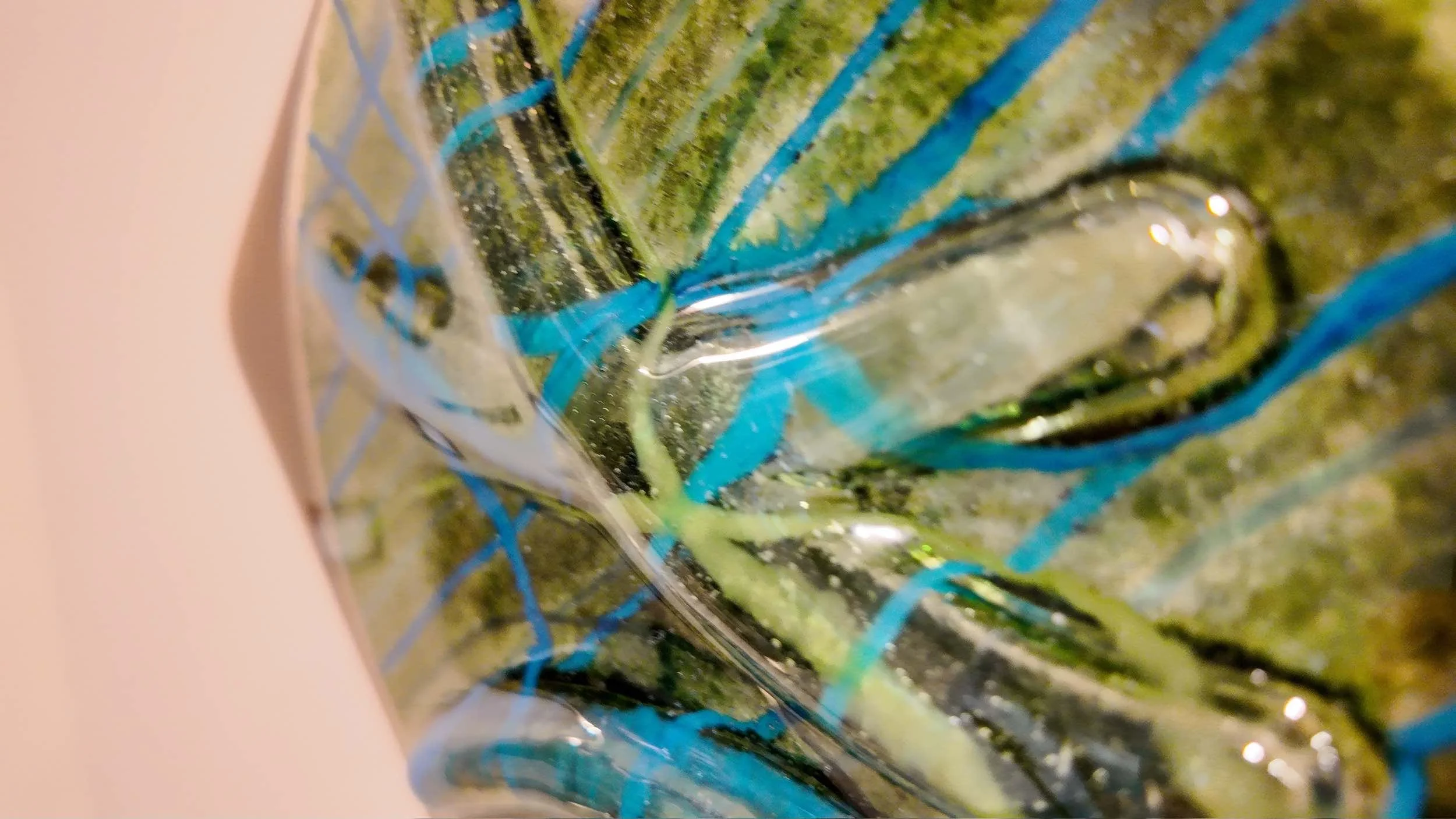 Close-up of a glass with a green beverage and colorful blue and green straw