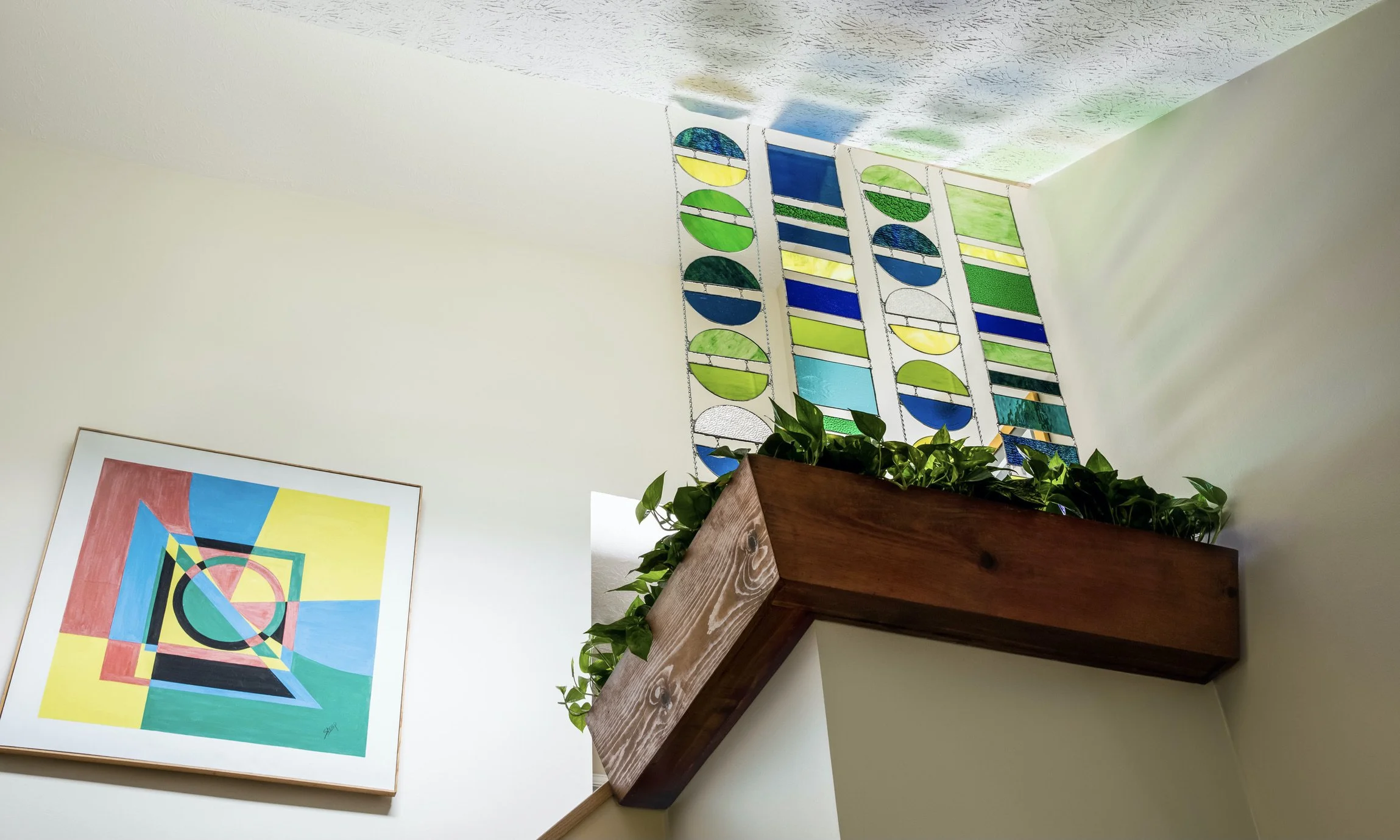 Full view of a 5-foot glass mobile designed to harness skylight sunlight, casting vibrant colored reflections across the walls and ceiling.