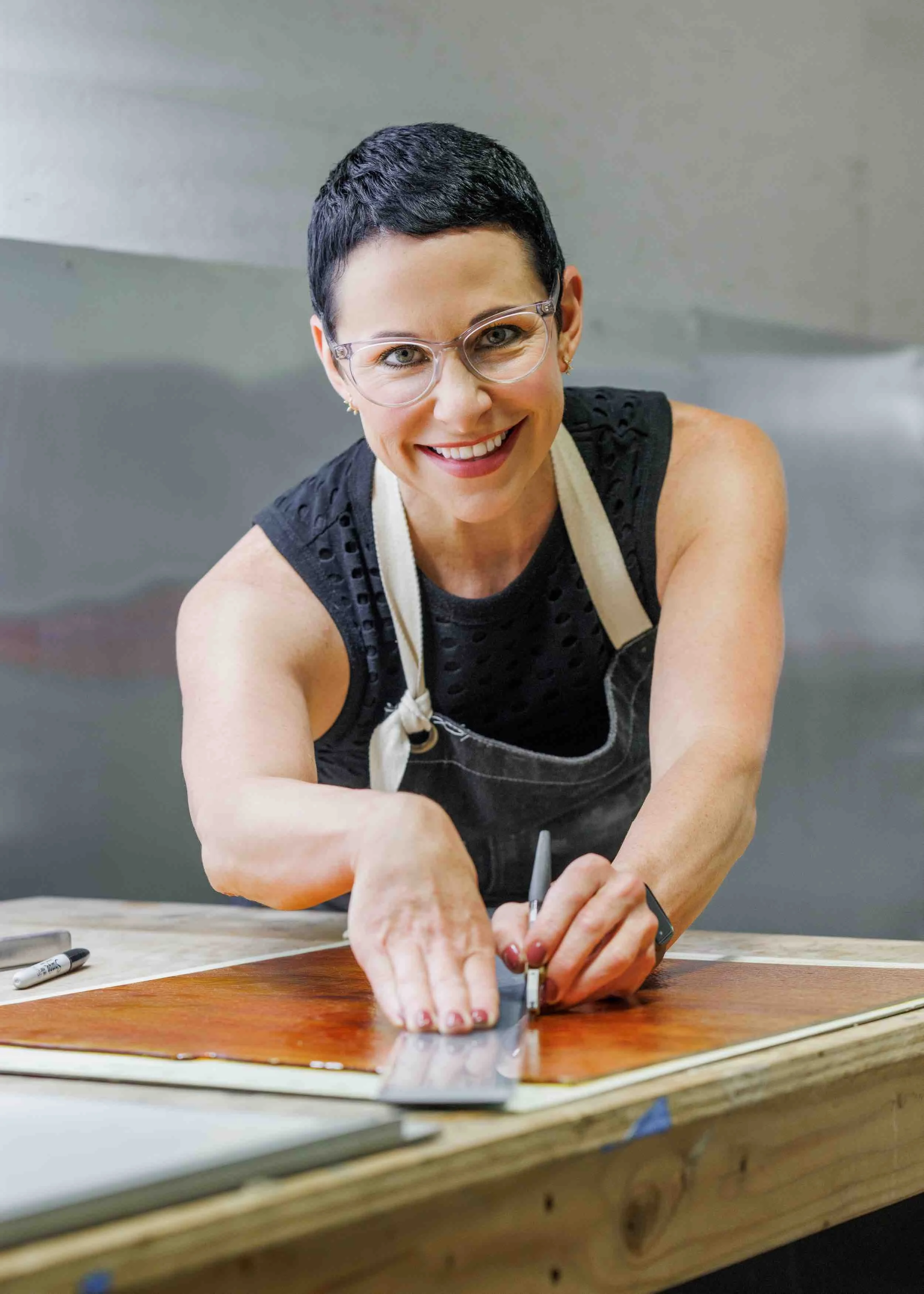Contemporary glass artist working in studio: Gina Word cutting glass for handcrafted fused glass sculptures in her Atlanta glass artist workshop.