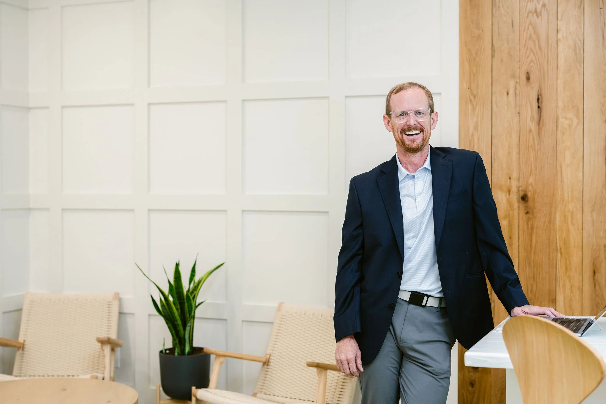 Dr Chad Bradford Scottsboro functional medicine doctor standing in a modern office space with chairs, a plant, and a wooden wall.