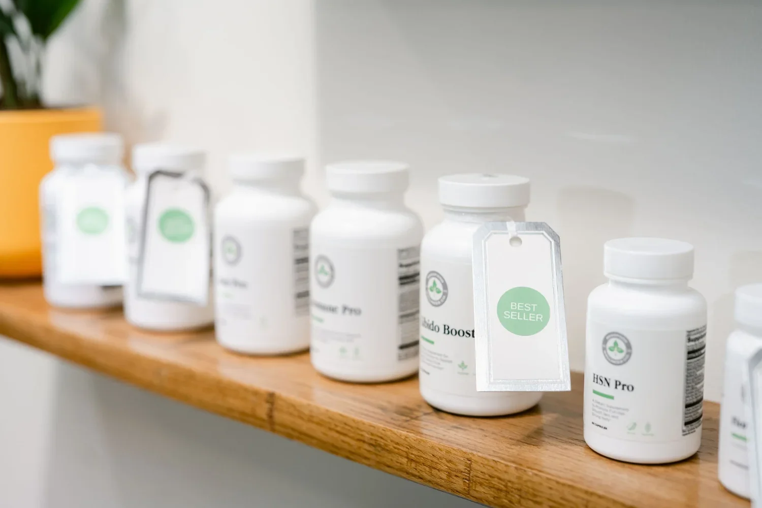A row of white supplement bottles with green labels on a wooden shelf, one marked 'BEST SELLER'.