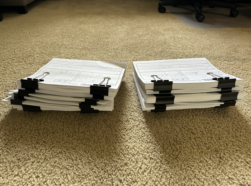 Two stacks of completed storyboards with black binder clips on a beige carpeted floor. 
