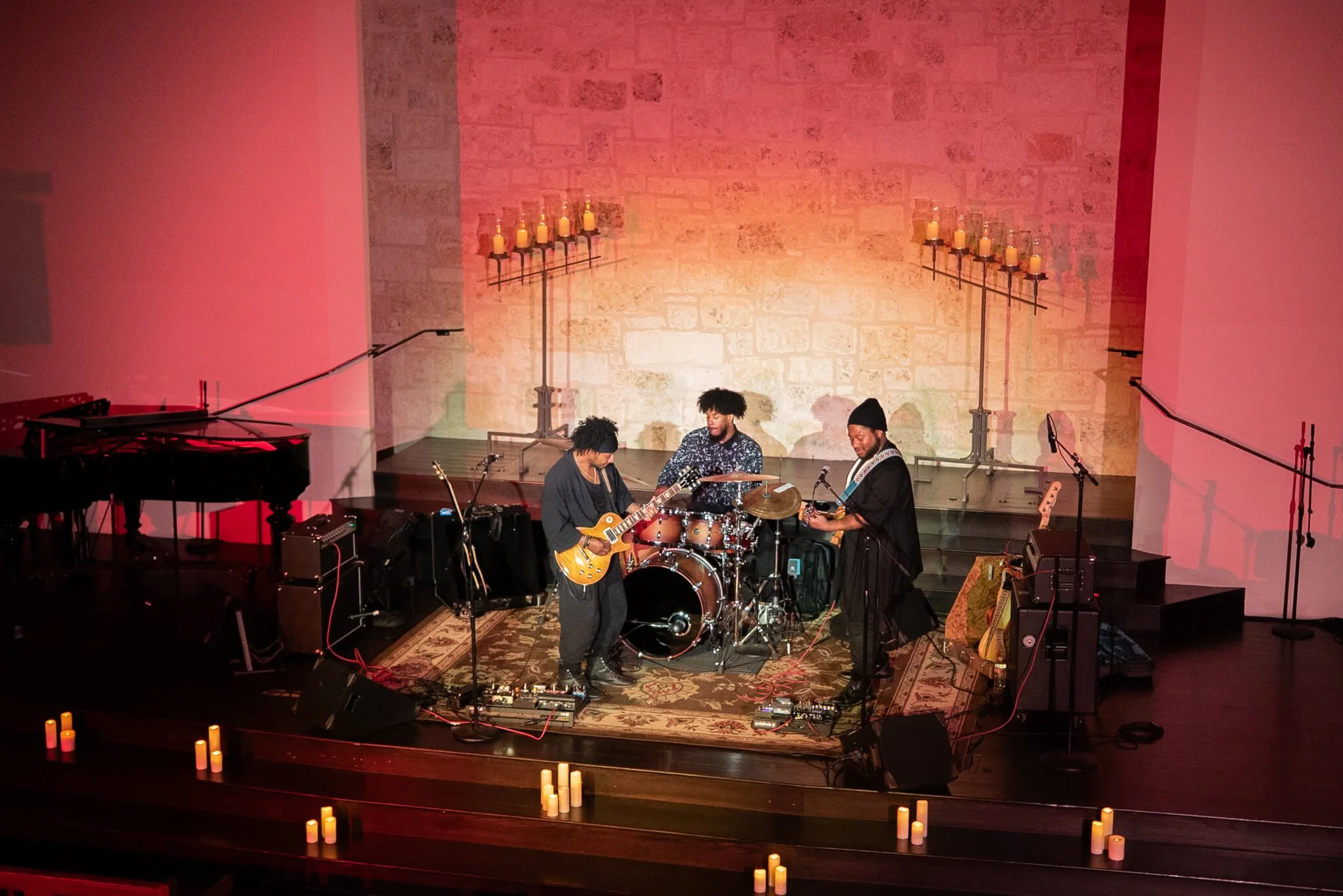 Three musicians performing on a candlelit stage at Riverbend Centre for the Arts